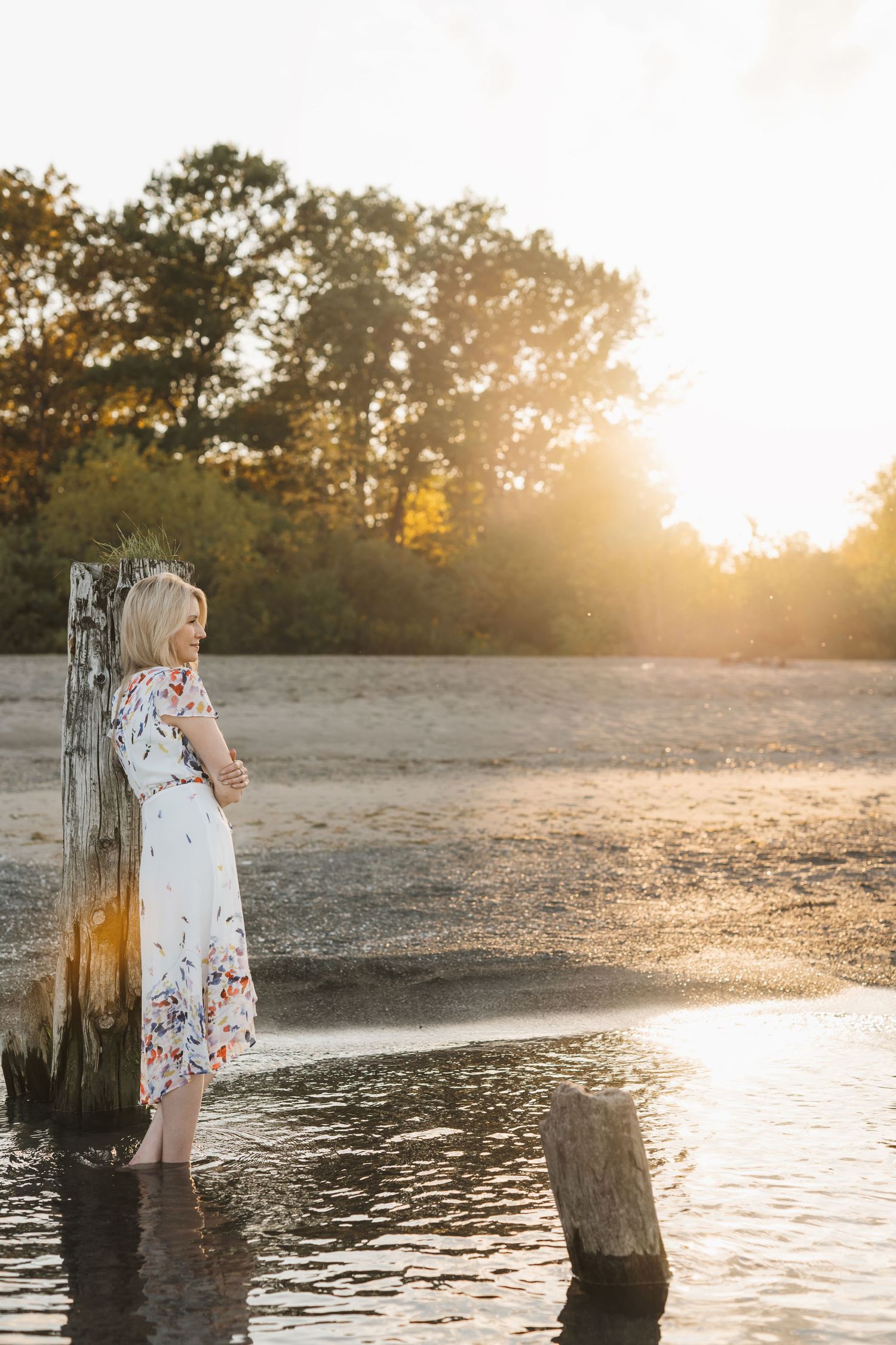 Michelle Hugill resting against a weathered wooden post in calm water at golden hour