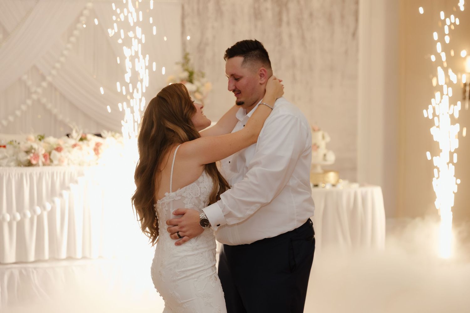 Bride and groom share their first dance surrounded by sparkling cold sparklers at a romantic wedding reception.