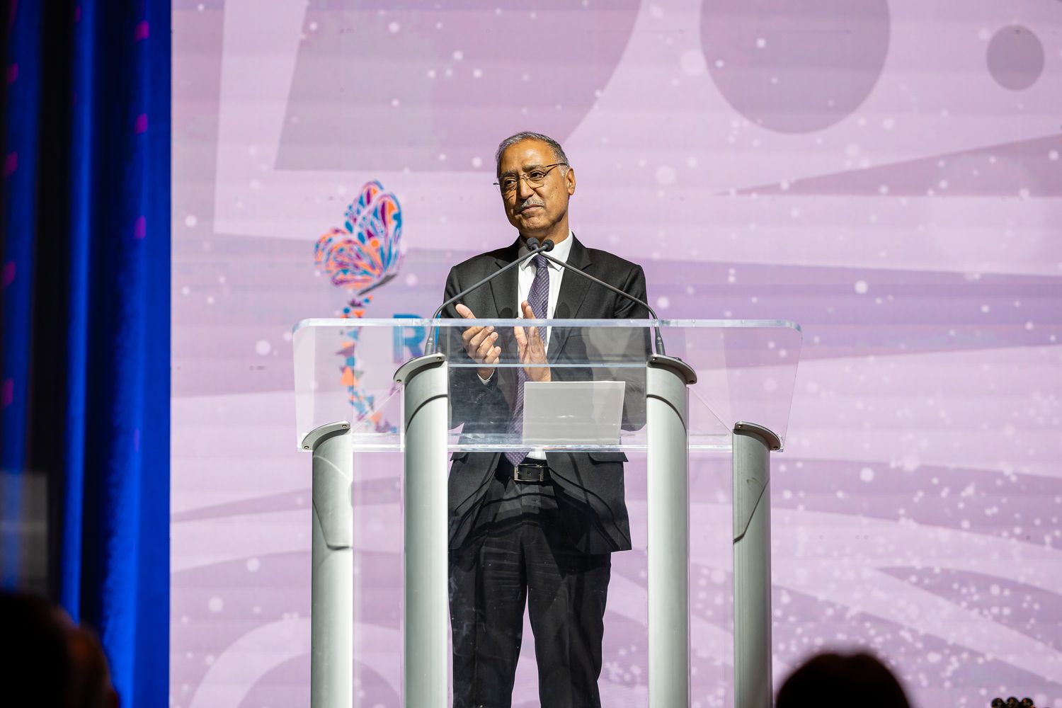 Speaker presenting at a podium during the RISE Awards ceremony with blue stage lighting.