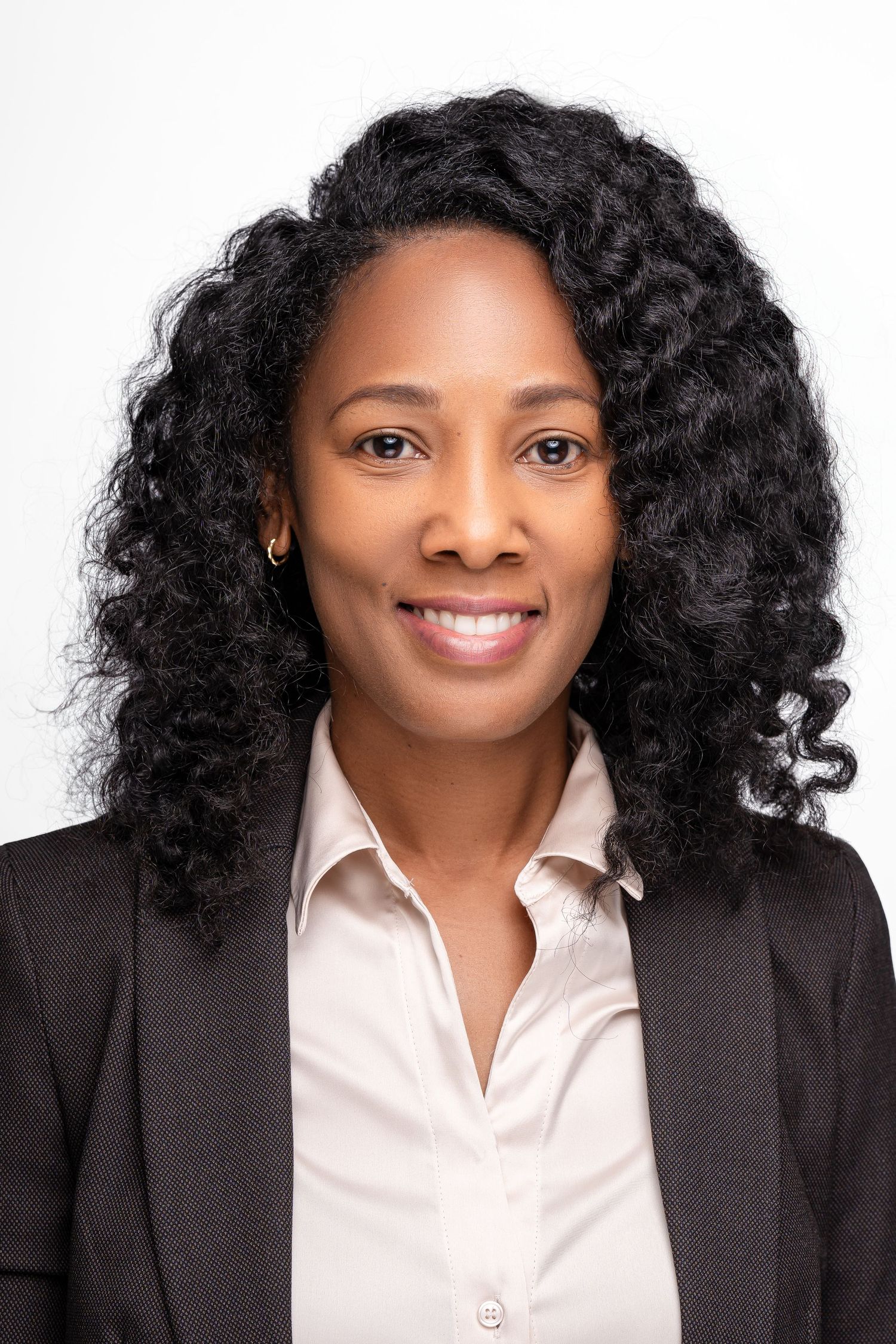 Professional headshots in black blazer and white shirt with natural curly hair.