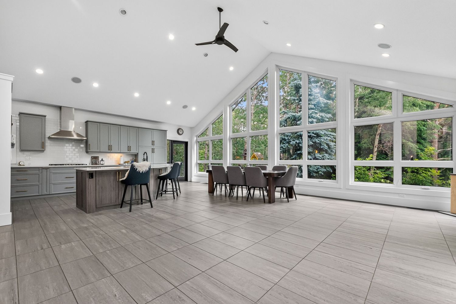 Spacious open-concept kitchen and dining area with vaulted ceilings, large windows, and modern gray cabinetry.