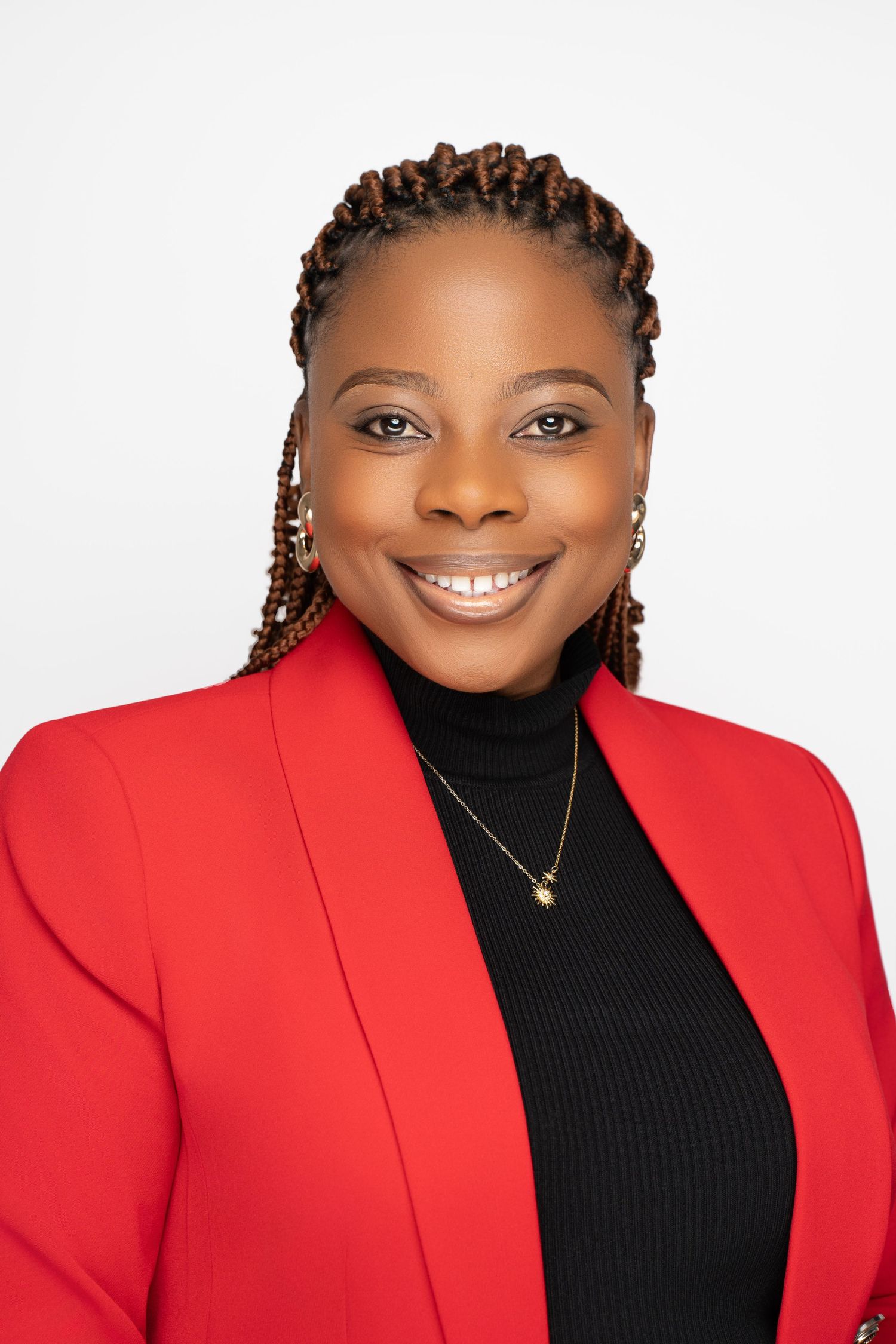 Professional portrait of person in red blazer and black turtleneck against white background.