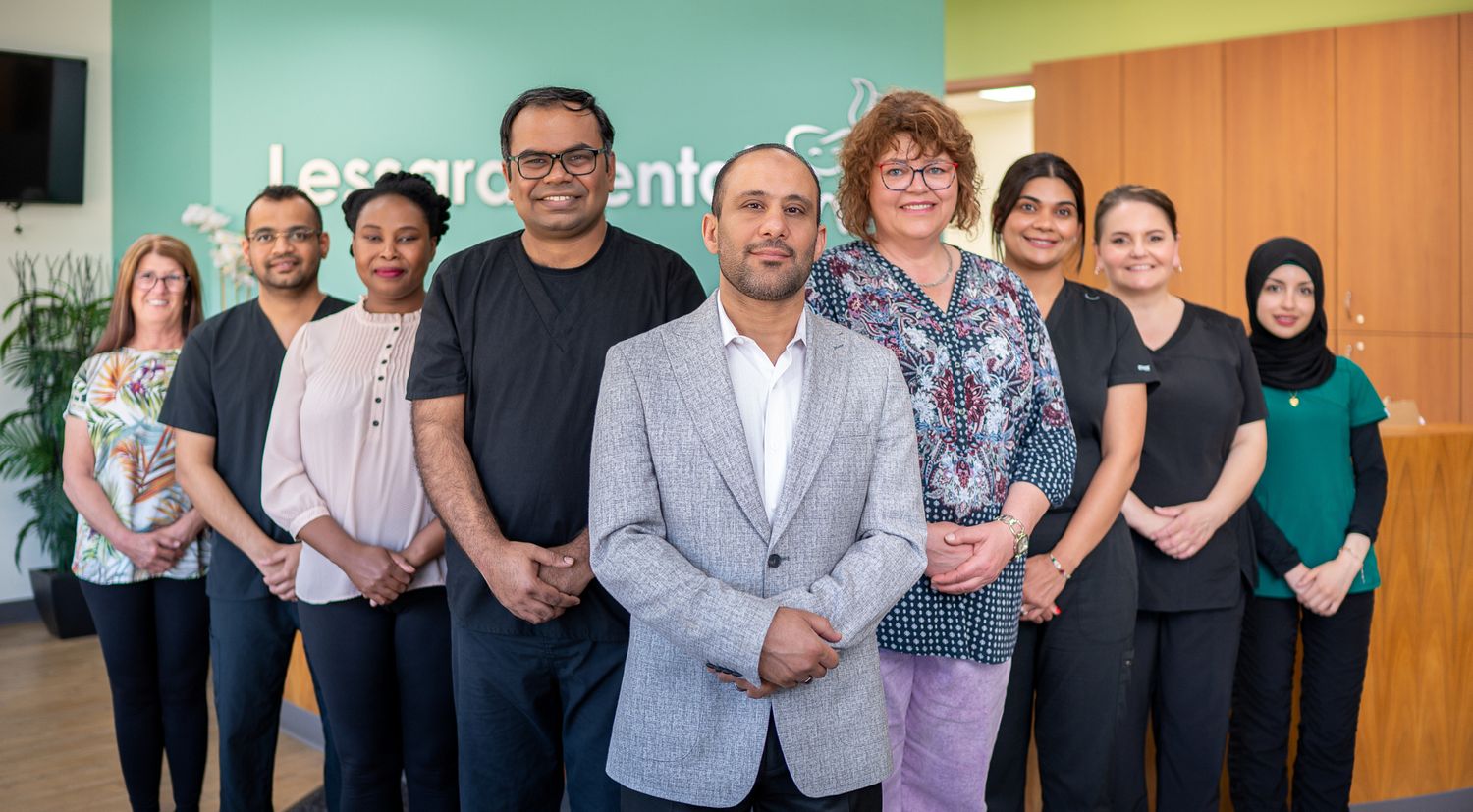 Professional team photo of diverse staff members standing together against colorful office wall.