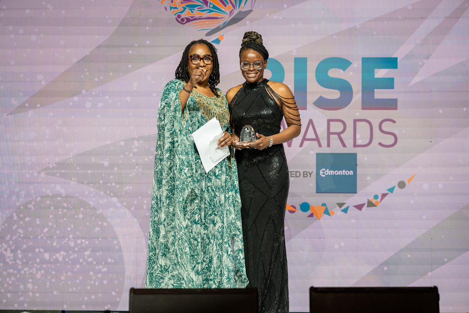 Two presenters embrace on stage at the RISE Awards ceremony.
