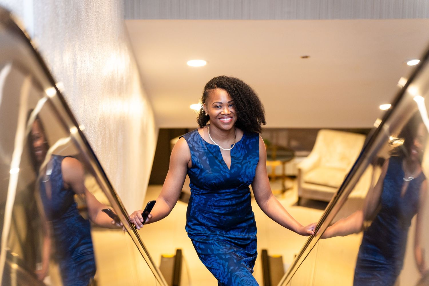 Guests in formal attire gather at an elegant event with a blue and gold balloon backdrop.