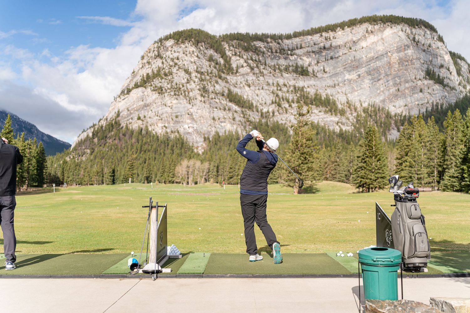 Scenic golf course with majestic mountain backdrop under blue skies.