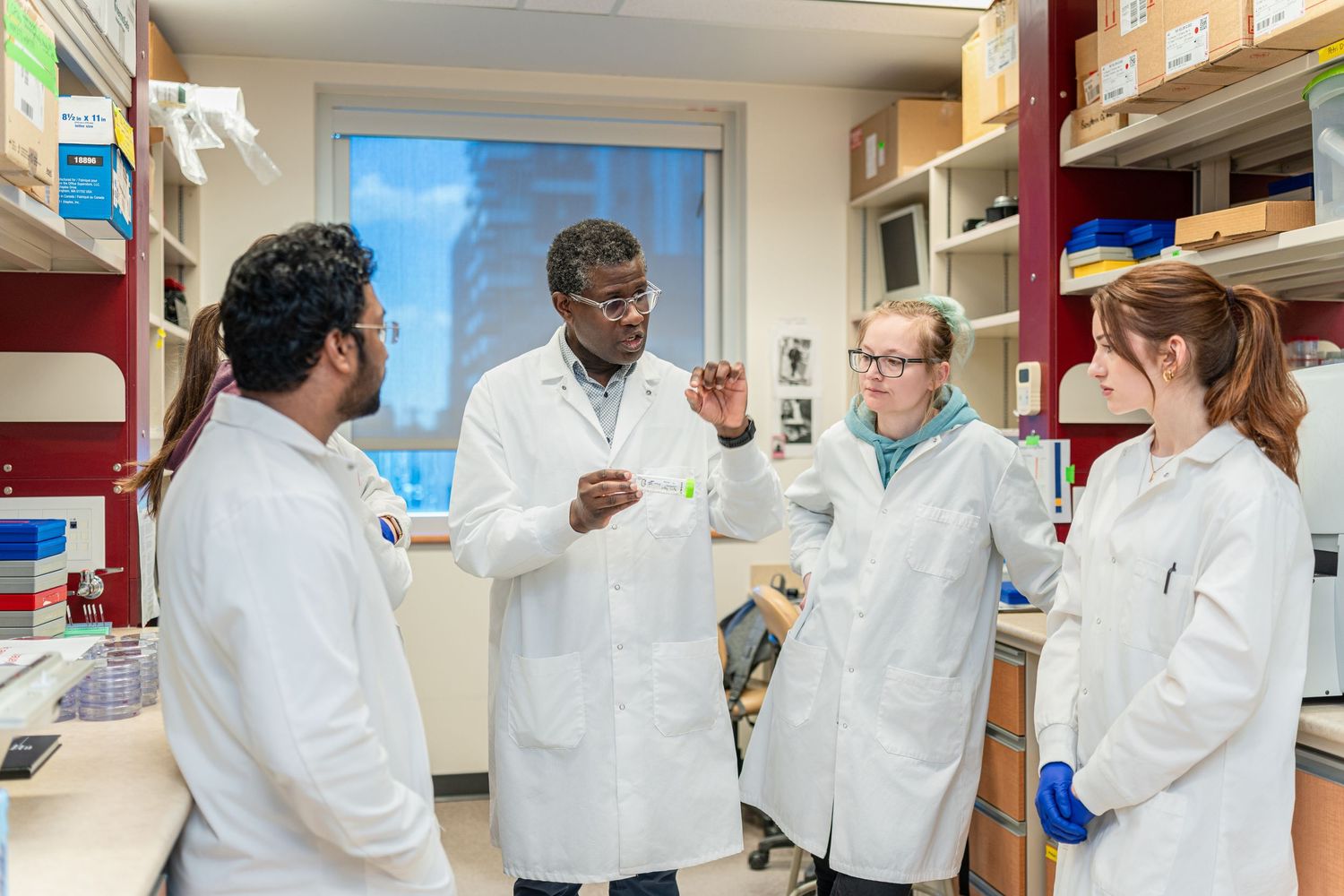 Research team in white lab coats collaborates in modern laboratory setting.
