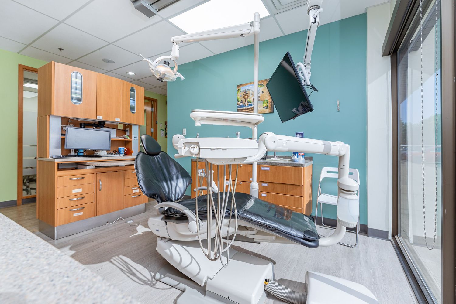 Modern dental examination room with blue walls, wooden cabinets and advanced medical equipment.