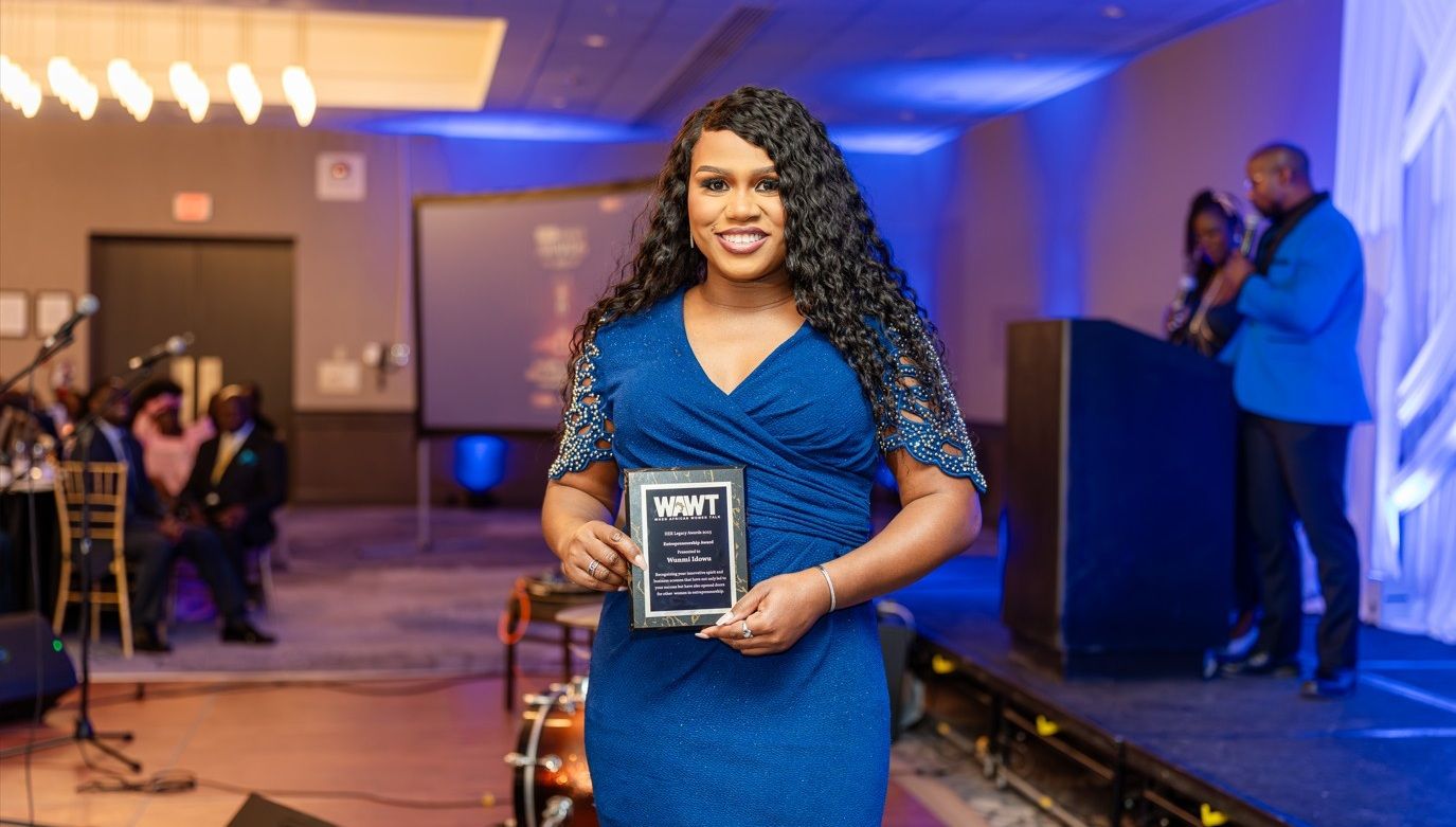 Awards ceremony with blue lighting and multiple attendees holding recognition plaques.