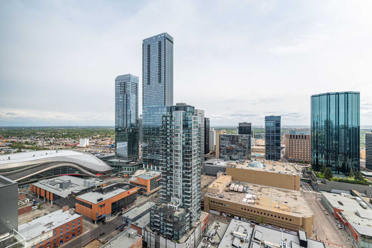 Aerial view of downtown Denver skyline featuring modern glass skyscrapers and urban development under a cloudy sky.