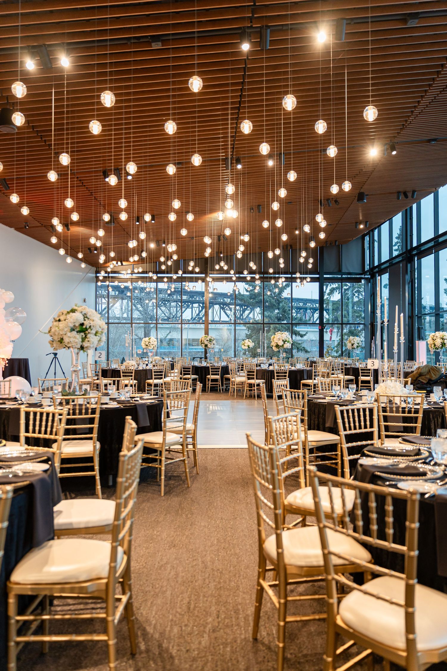 Reception venue with dramatic lighting featuring rows of hanging bulbs over dining tables.