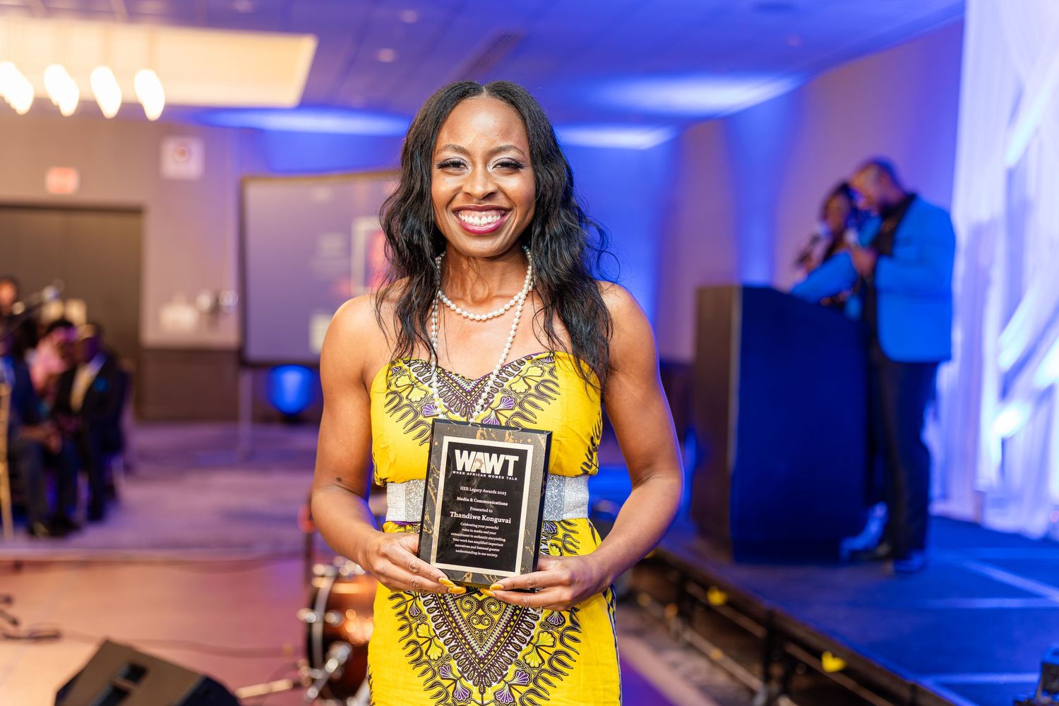 Recipients in yellow and blue formal wear display awards at an elegant ceremony.