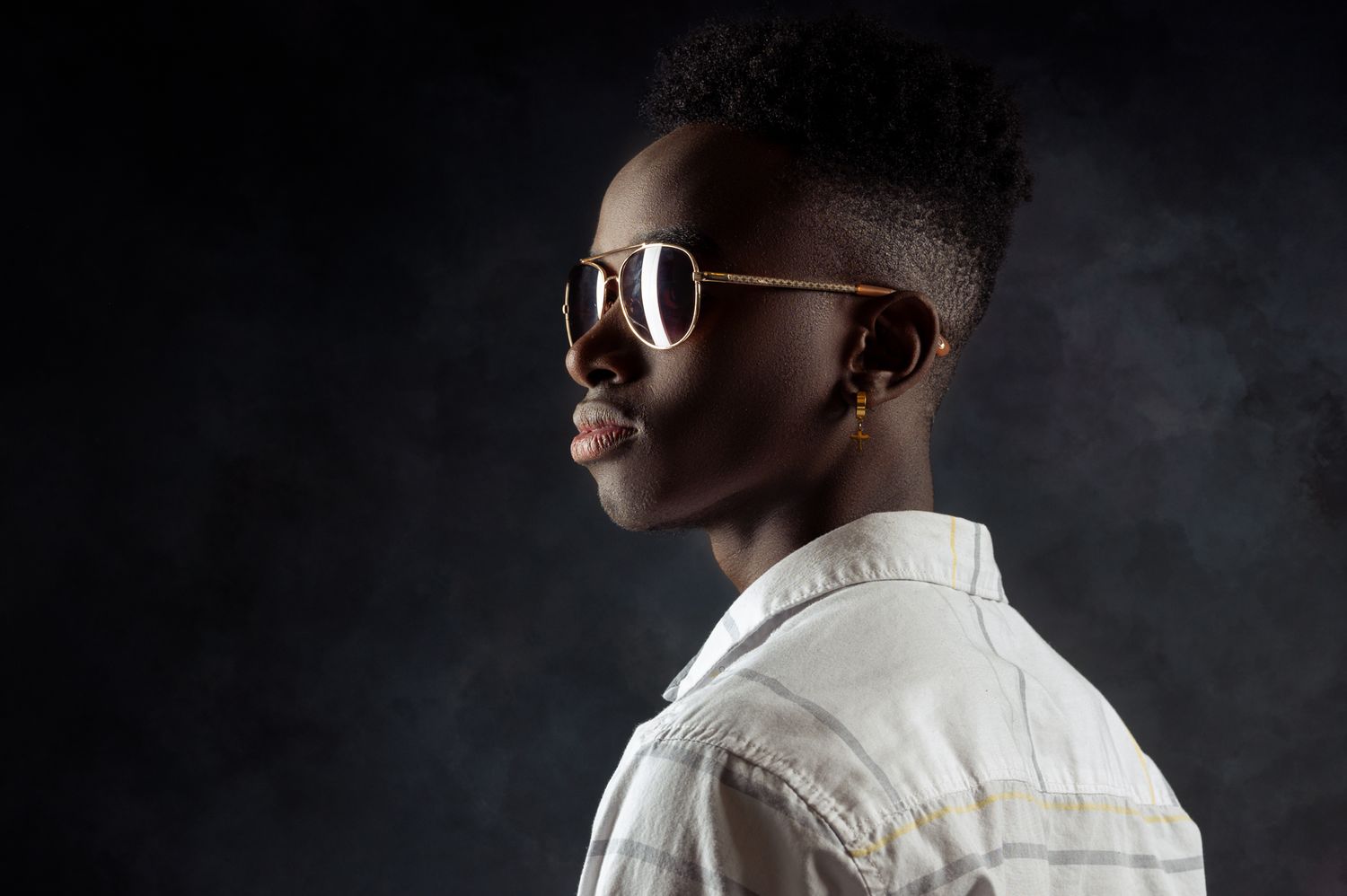 Stylish portrait against dark background with sunglasses and white shirt.