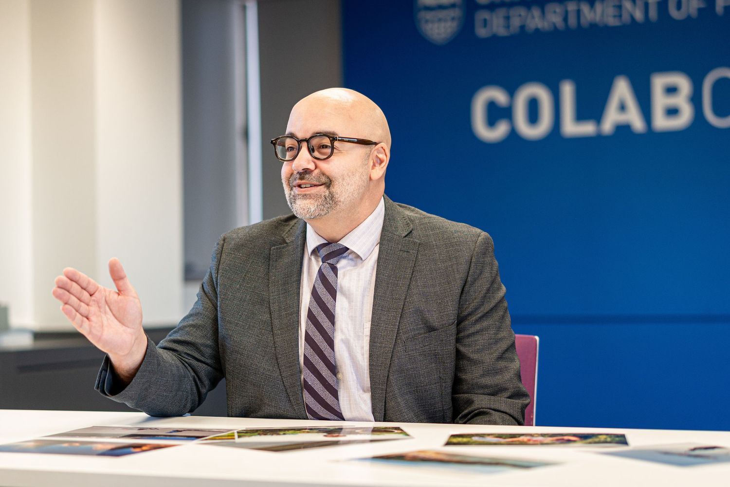 Professional in gray suit speaks animatedly at conference table.