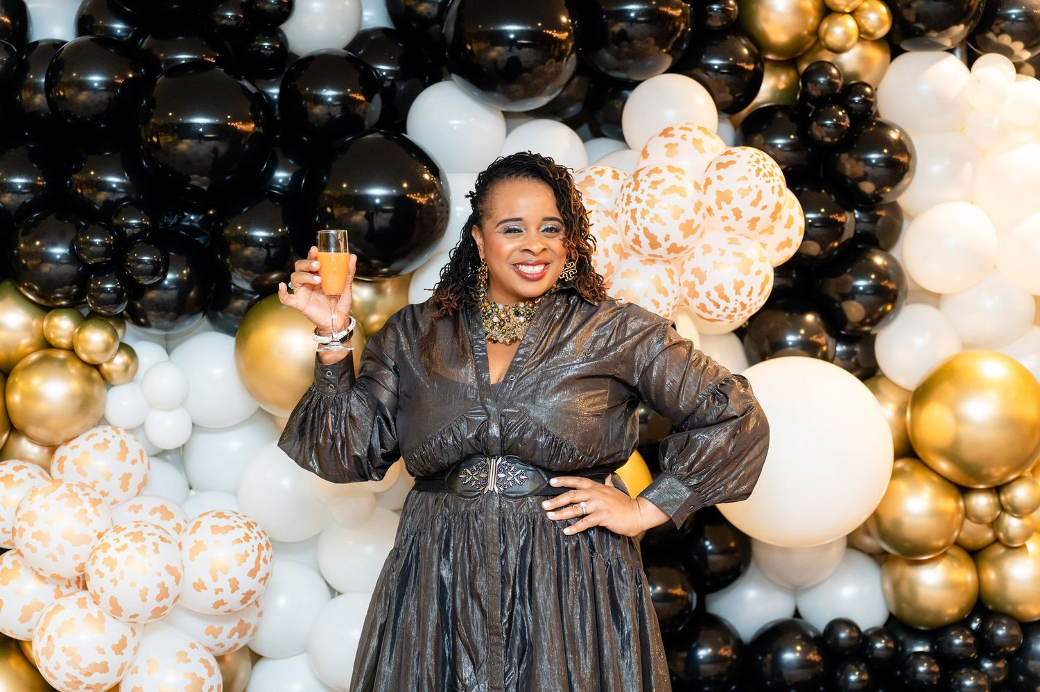 Celebratory scene with black and gold balloon arch backdrop at formal event.