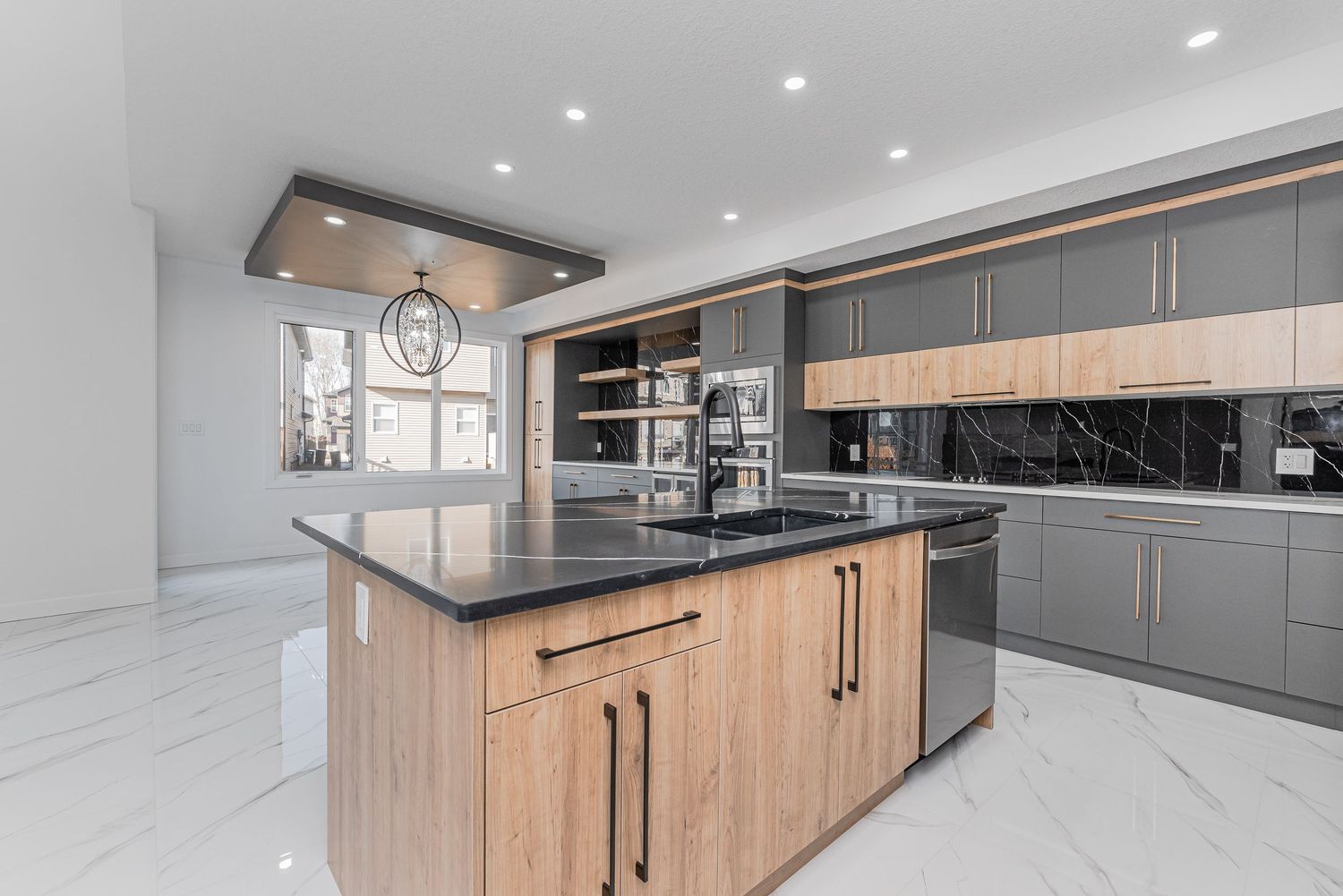 Modern kitchen with gray cabinets, wood island, black countertops, marble floors, and built-in appliances.