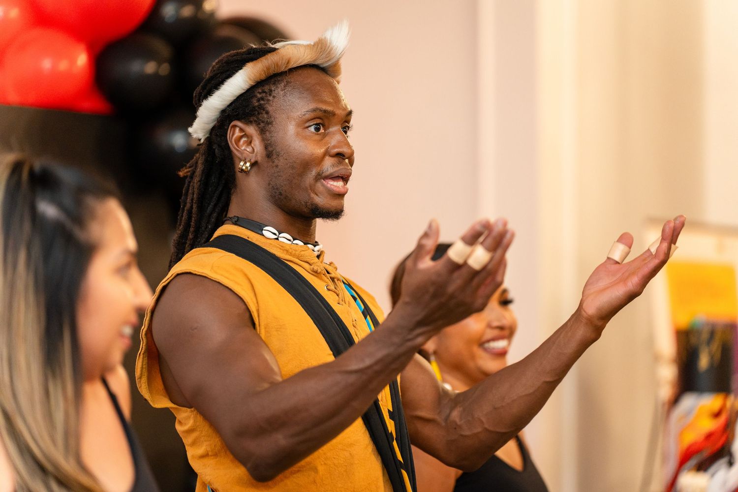 An animated performer in yellow attire gesturing expressively during an indoor event.