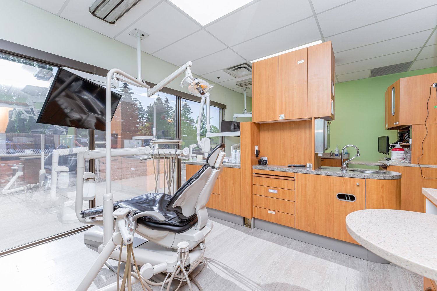 Dental examination room with modern equipment and large windows providing natural light.