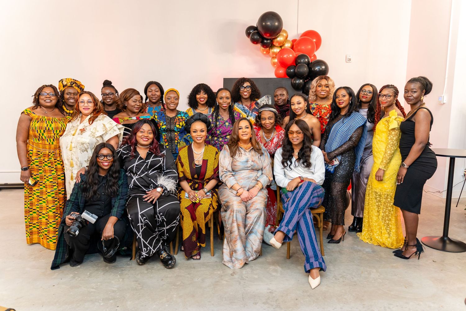 Large group photo showcasing vibrant African prints and formal attire at an indoor celebration.