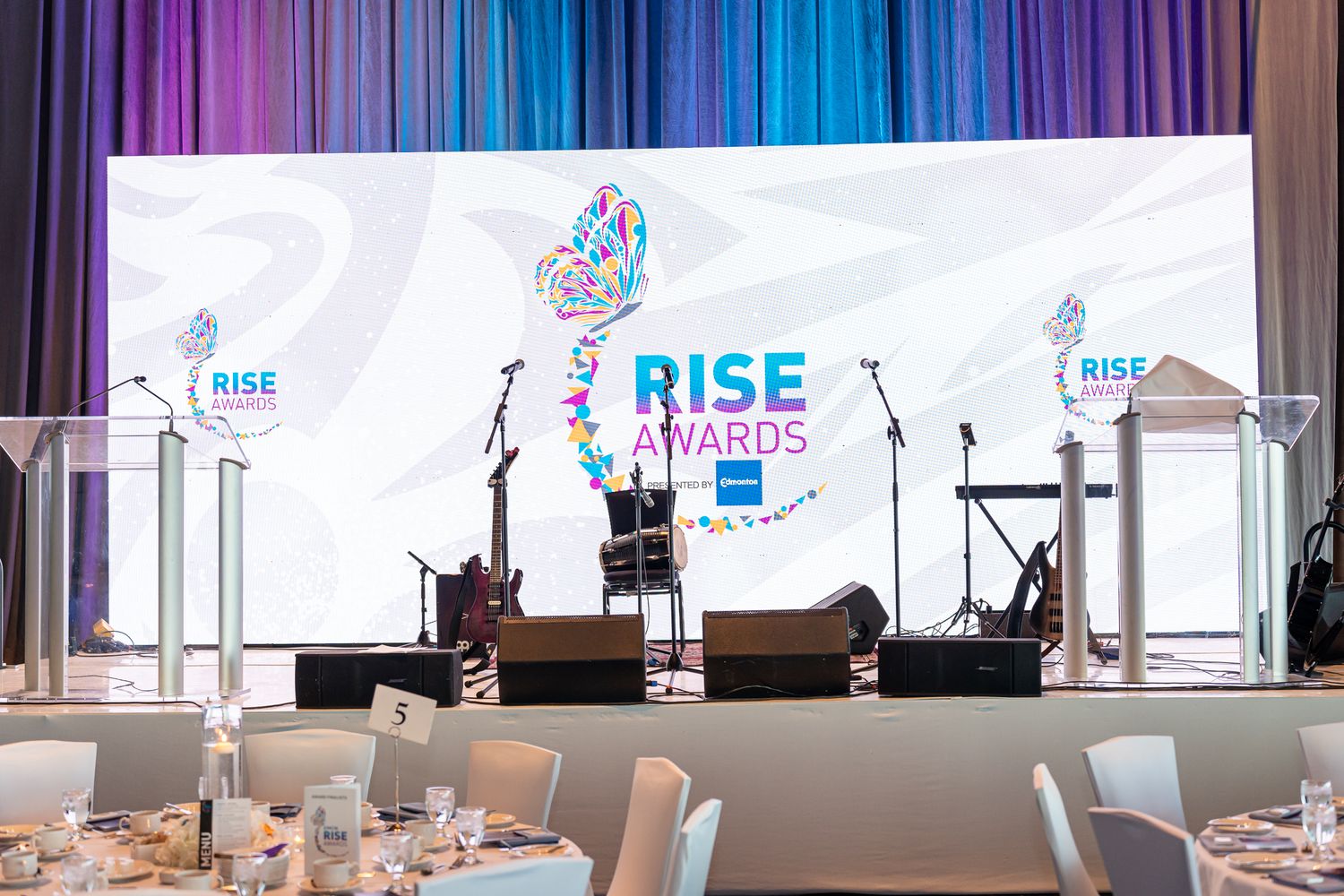 Conference stage setup with RISE branding and multiple podiums against blue lighting.