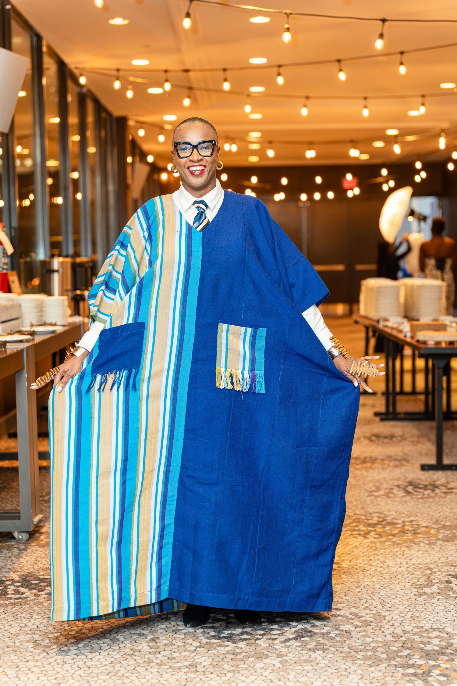 Person displaying a bright blue and white striped poncho under ambient string lighting.