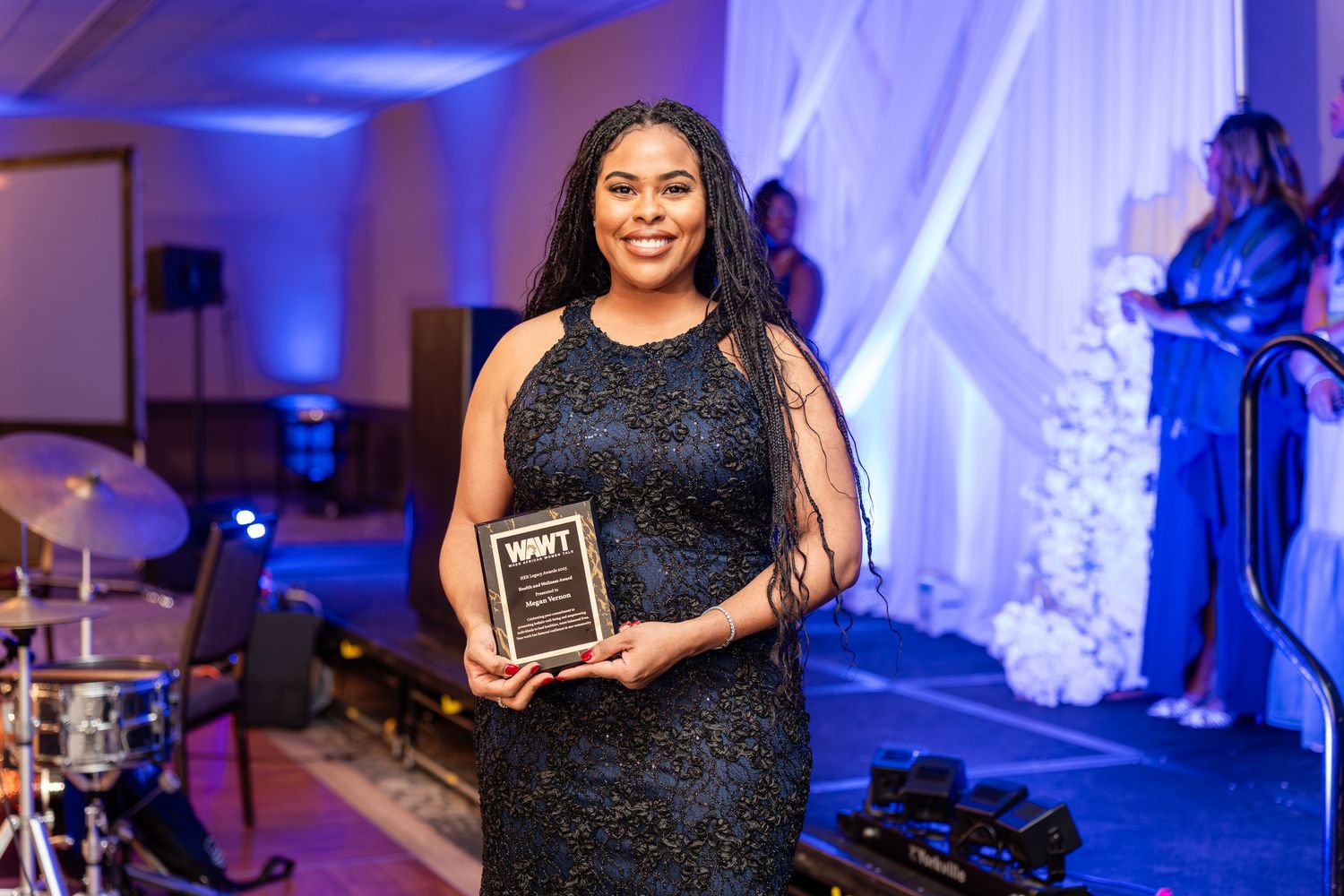 Award recipients pose with plaques at an evening ceremony with blue ambient lighting.
