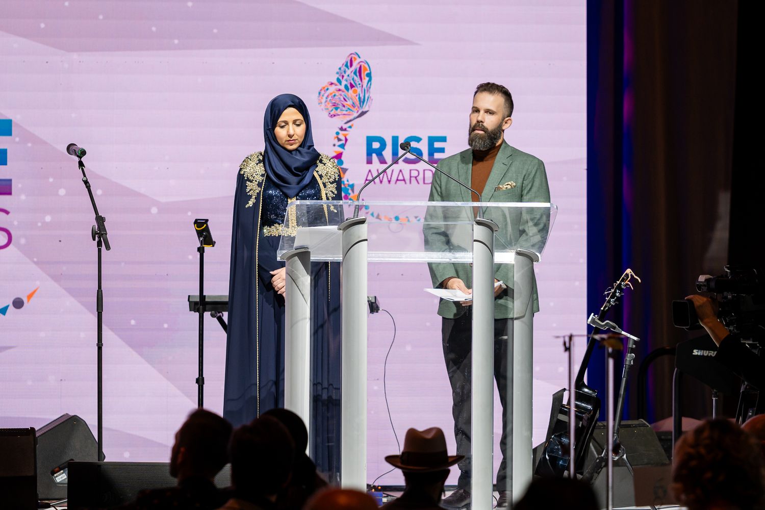 Professional awards ceremony stage with white podiums and RISE branding backdrop.