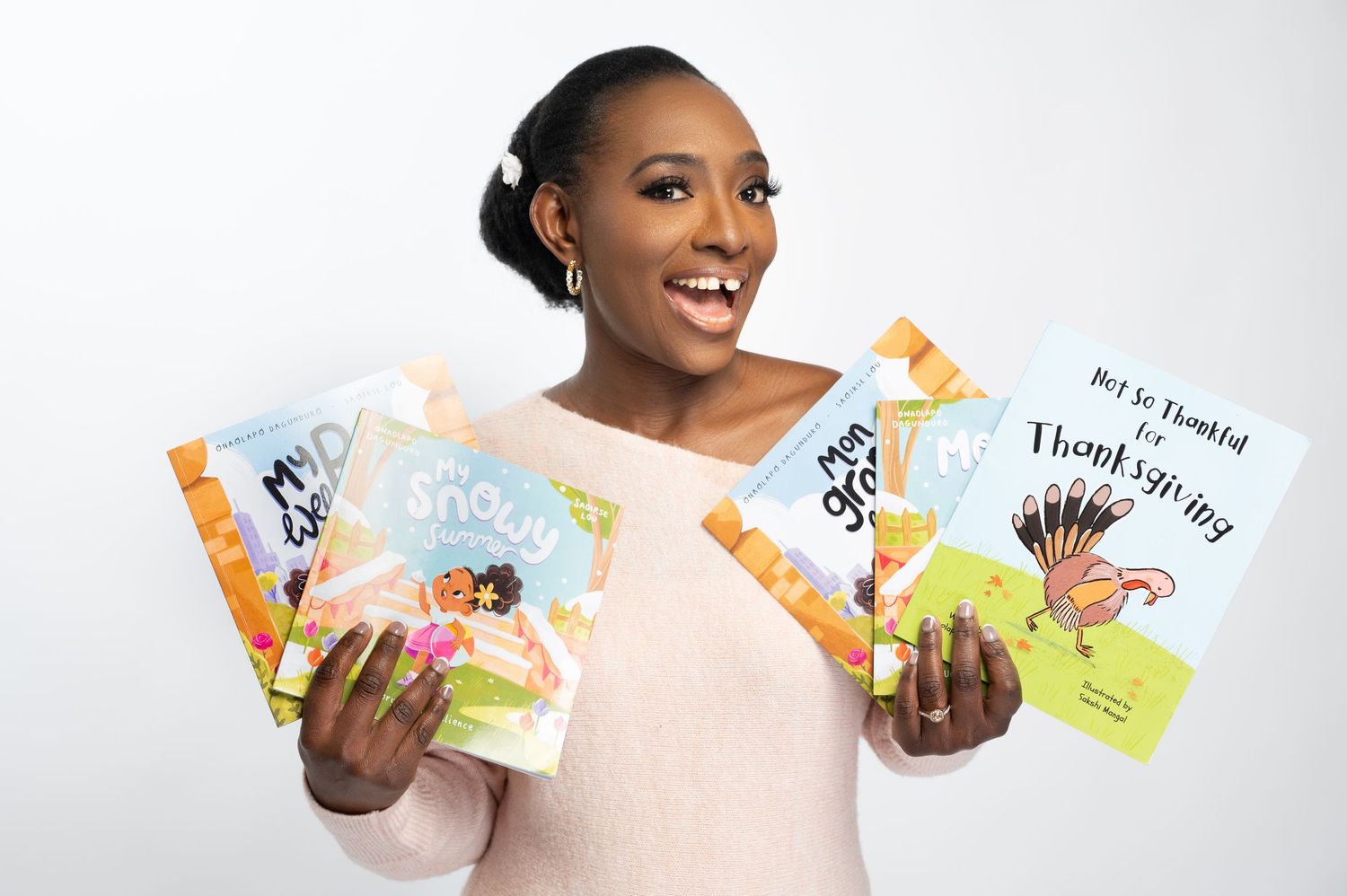 Smiling person holding children's books against white background.