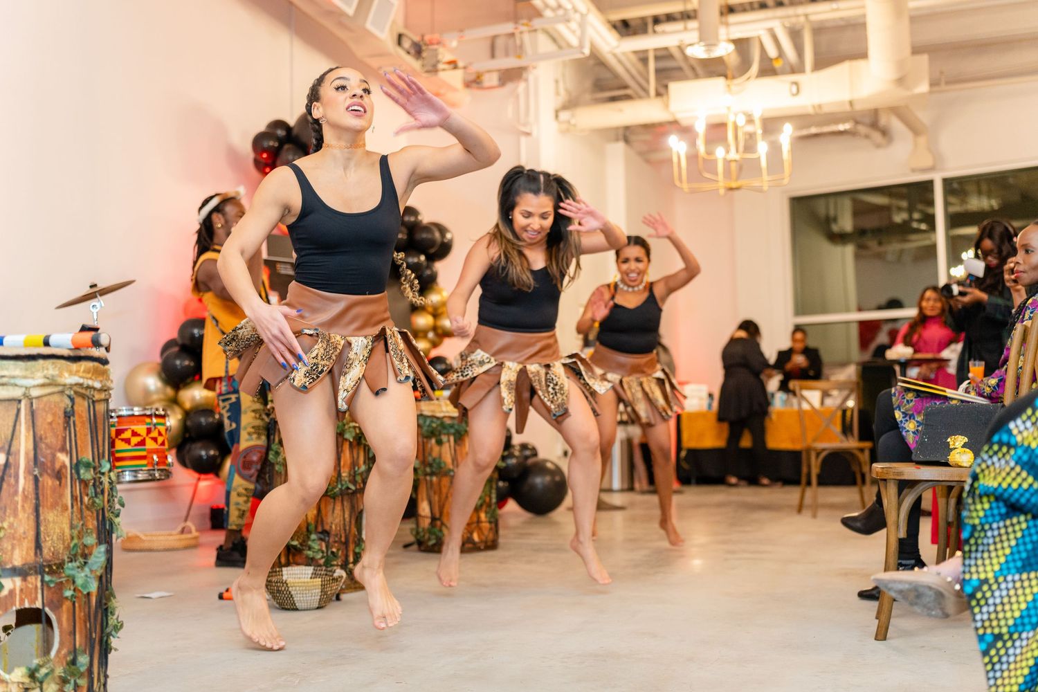 Dancers performing energetic movements in a bright studio space with festive decorations.