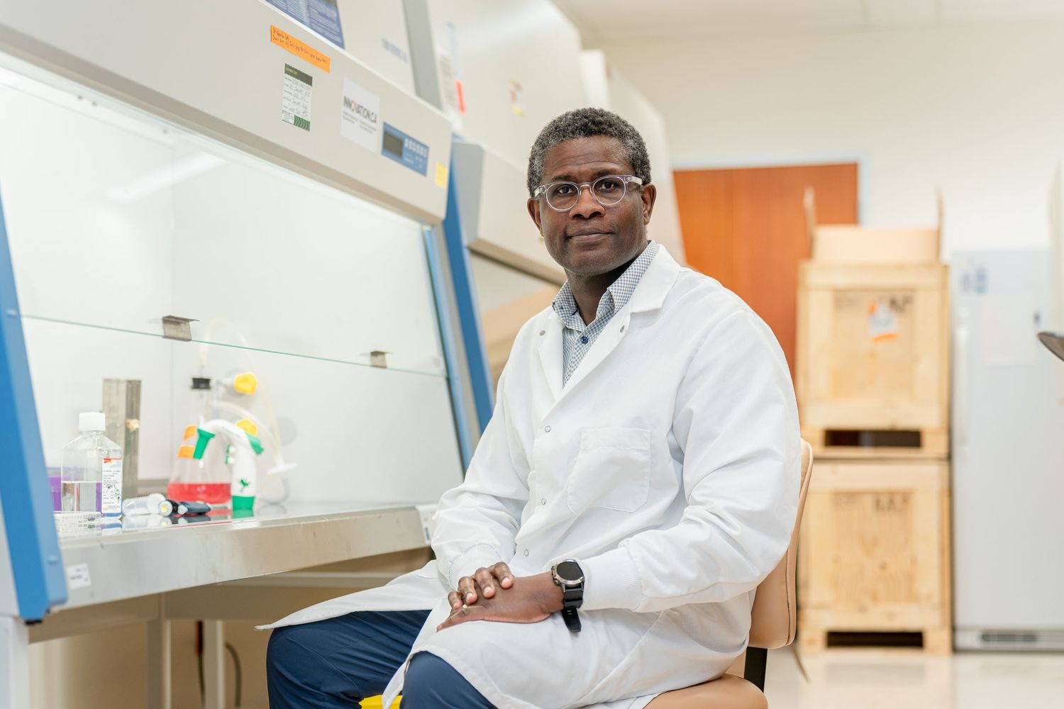 Scientist in white lab coat sits in research laboratory.