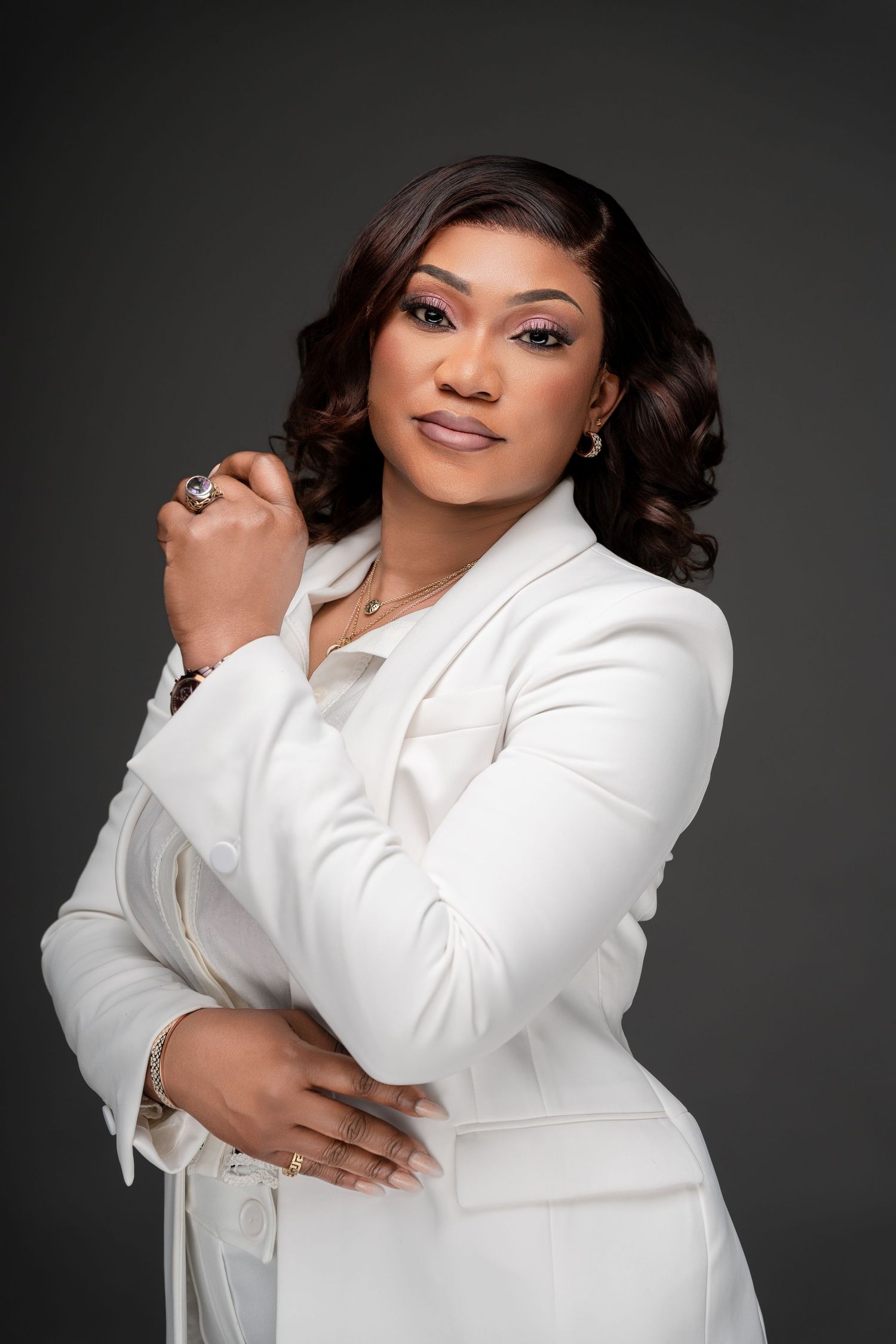 Professional portrait series in white blazer against dark backdrop with dramatic lighting.