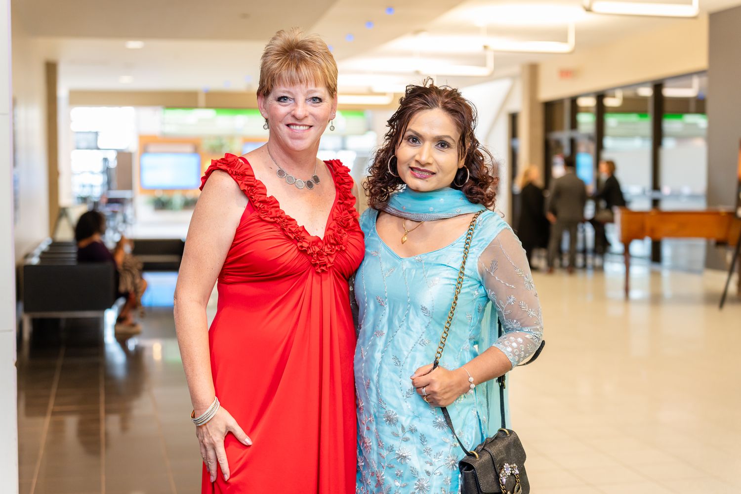 Attendees in formal attire gathered in a bright hallway setting.