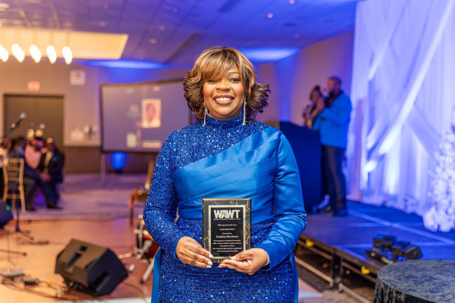 Award winners showcase their plaques at a formal event with blue lighting and decor.