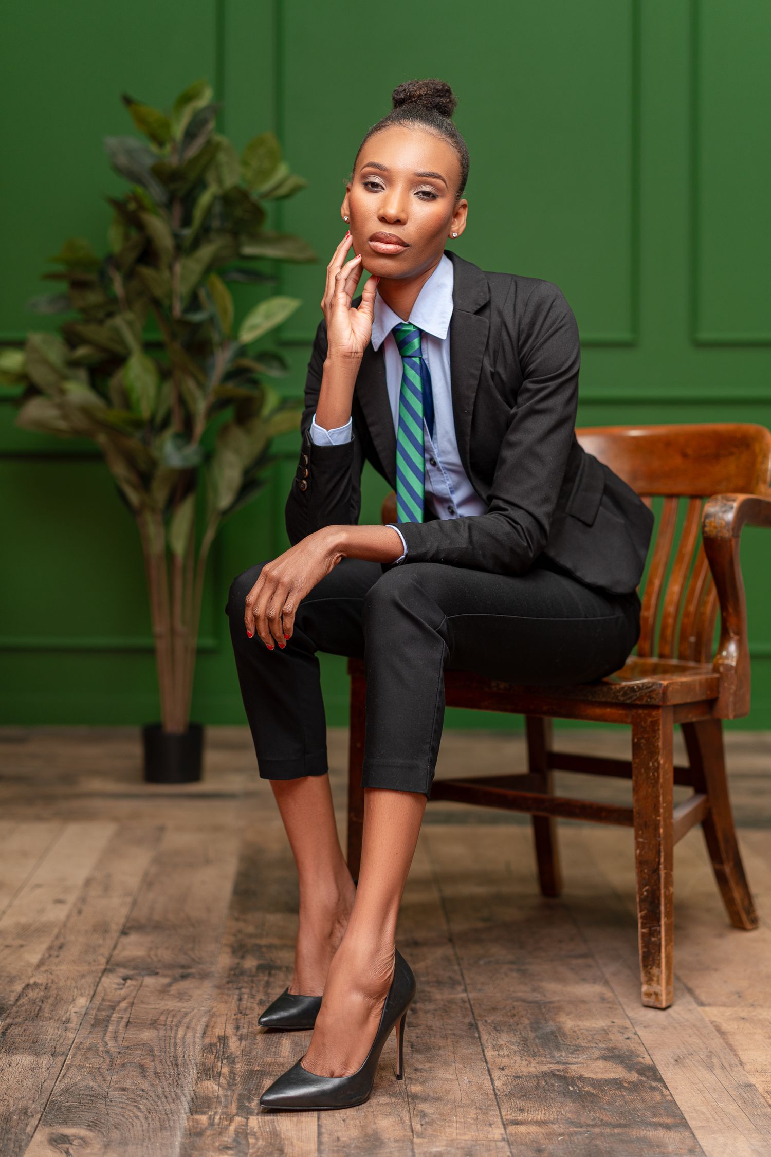 Professional portraits in business suit against green paneled wall with wooden bench.
