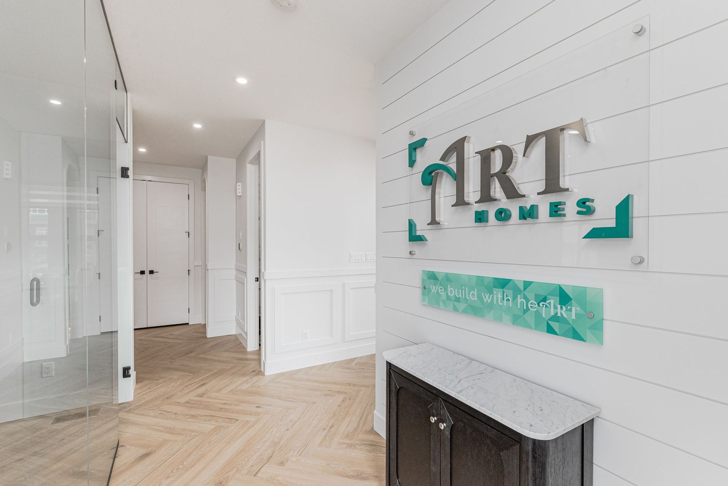 Modern ART Homes office entryway with shiplap walls, herringbone floors, and elegant marble console table.
