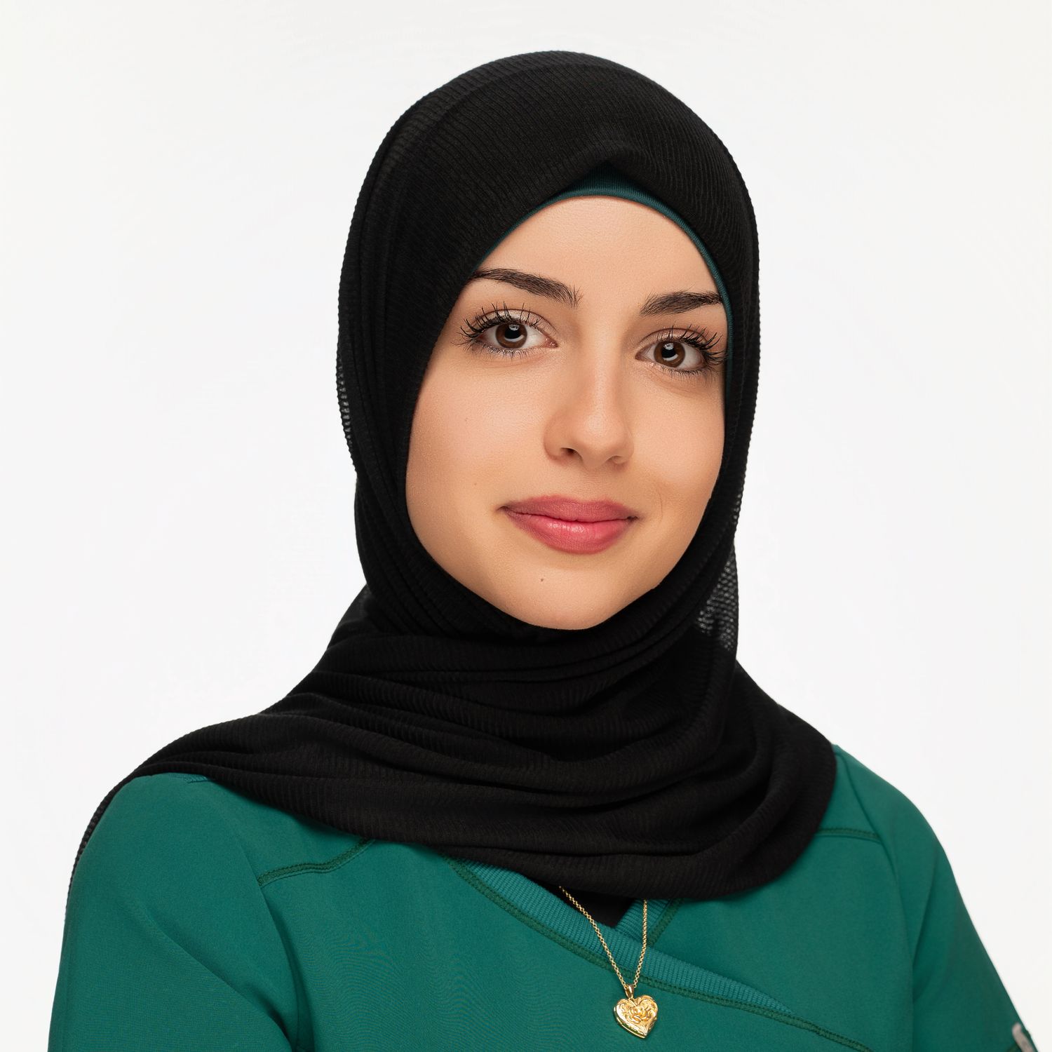 Professional portrait of person in emerald green top and black hijab against white background.