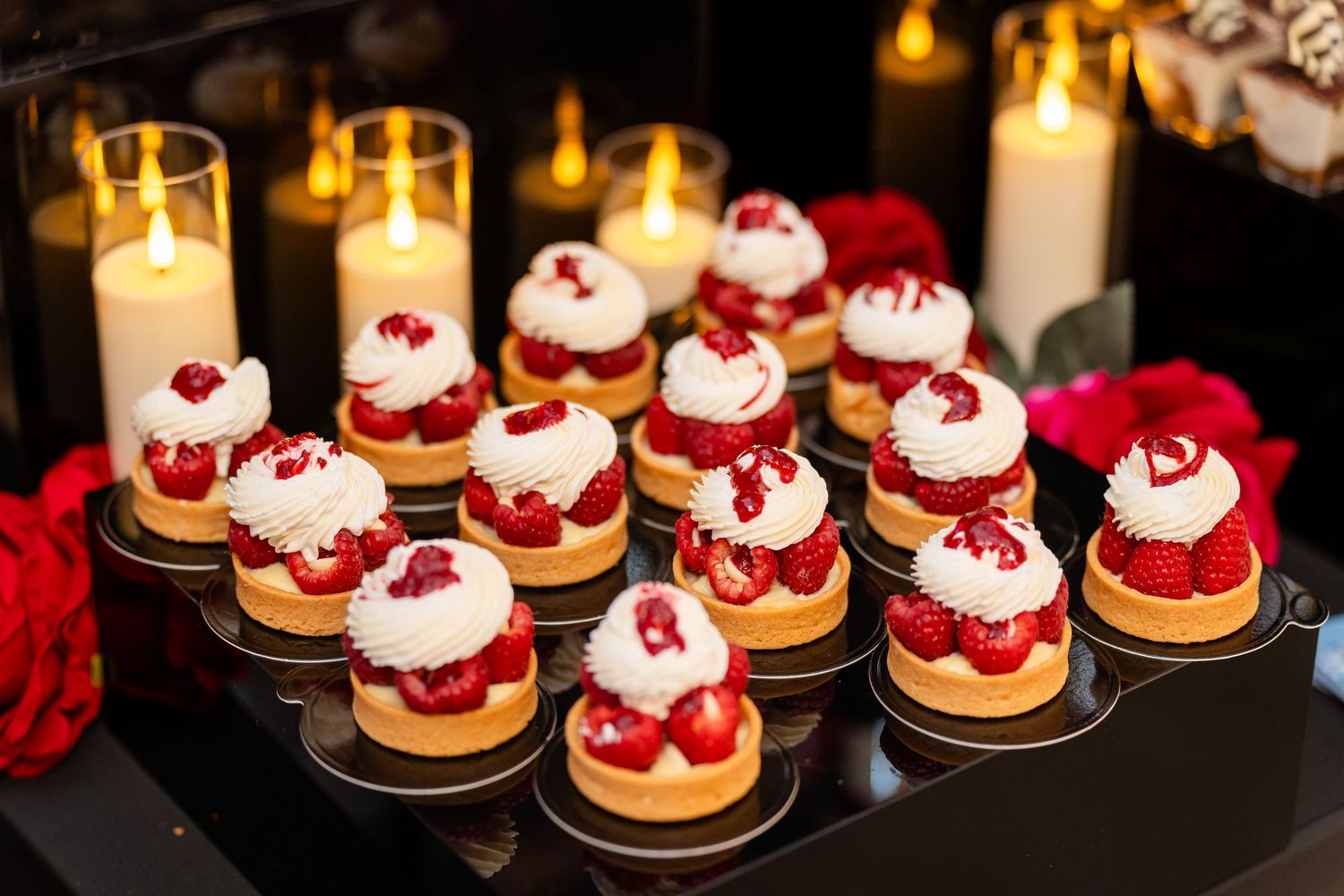Elegant dessert display featuring red velvet mini cakes topped with berries and cream.
