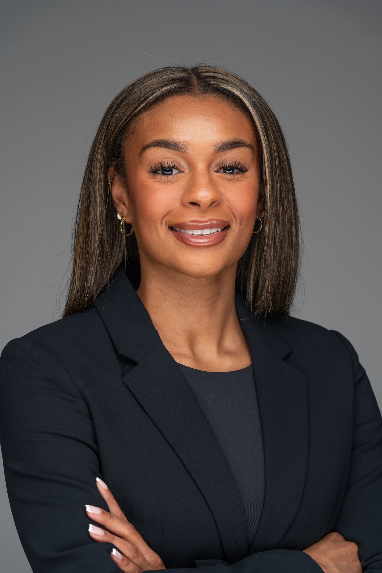 Professional headshots of someone in dark blazer against grey studio background.