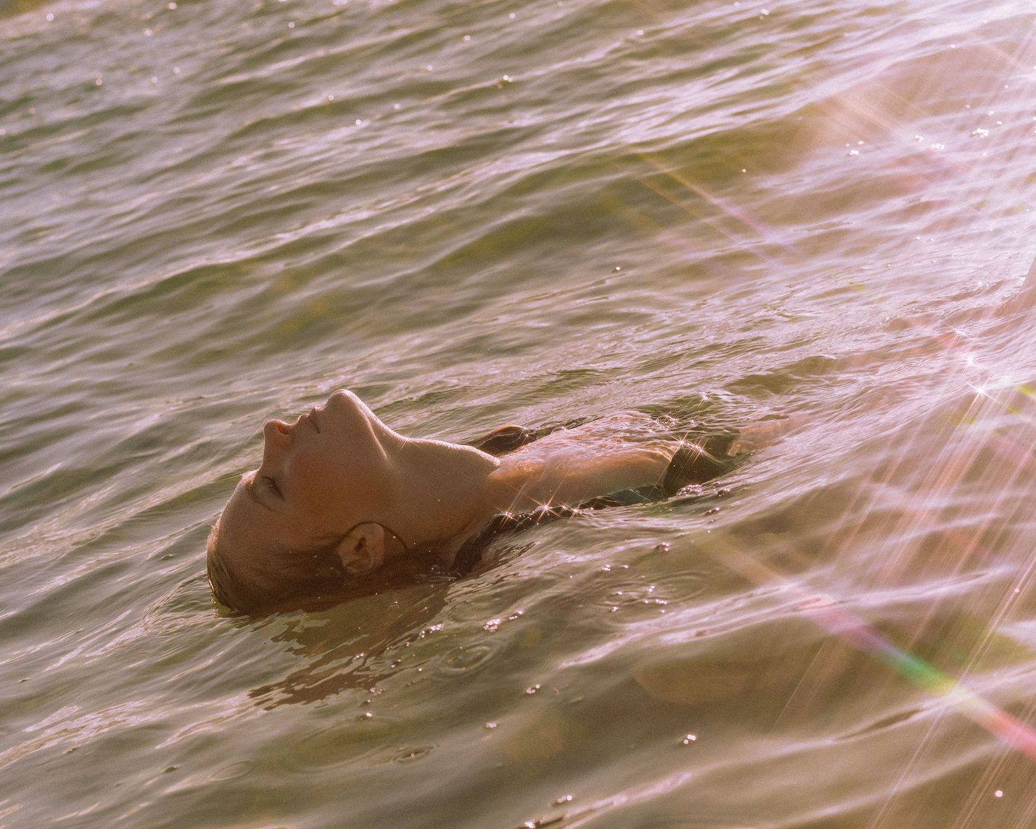 A person floats peacefully in calm water during sunset creating a serene and tranquil scene.