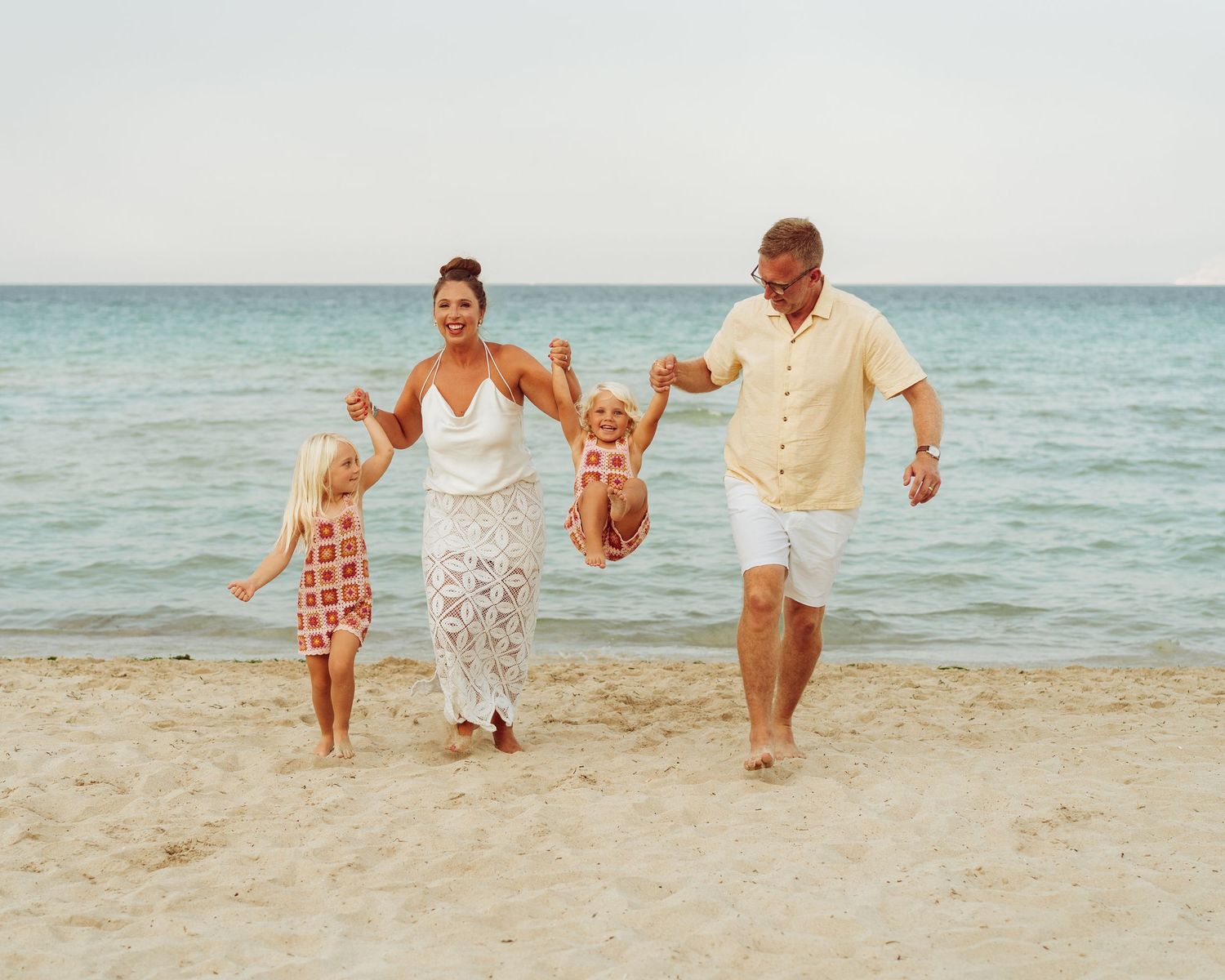 Family running and playing together on a sunny beach.