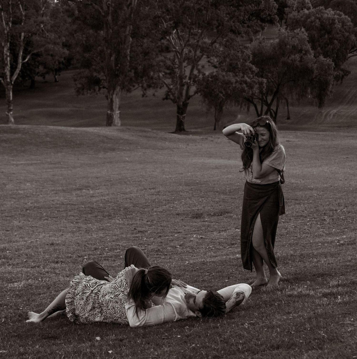 A person rolling down a grassy hill in black and white, creating a playful tumbling motion in sequence.