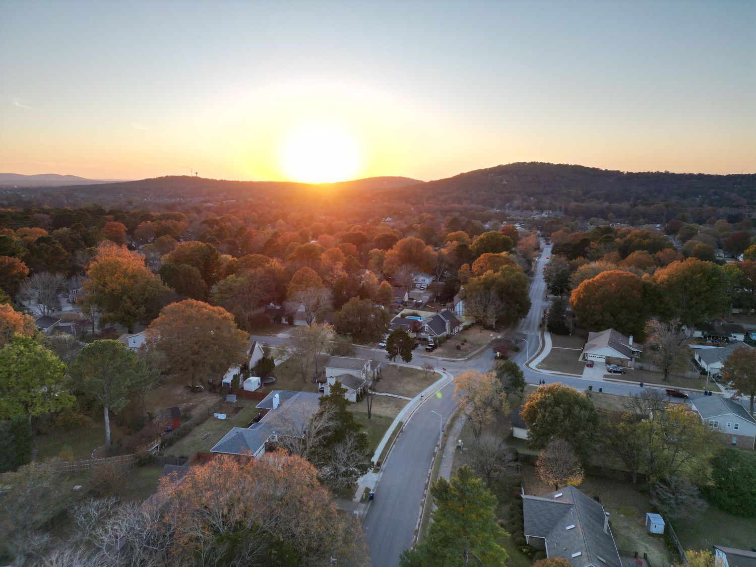 Aerial panorama of a suburban neighborhood at sunset with mountains in the background.
