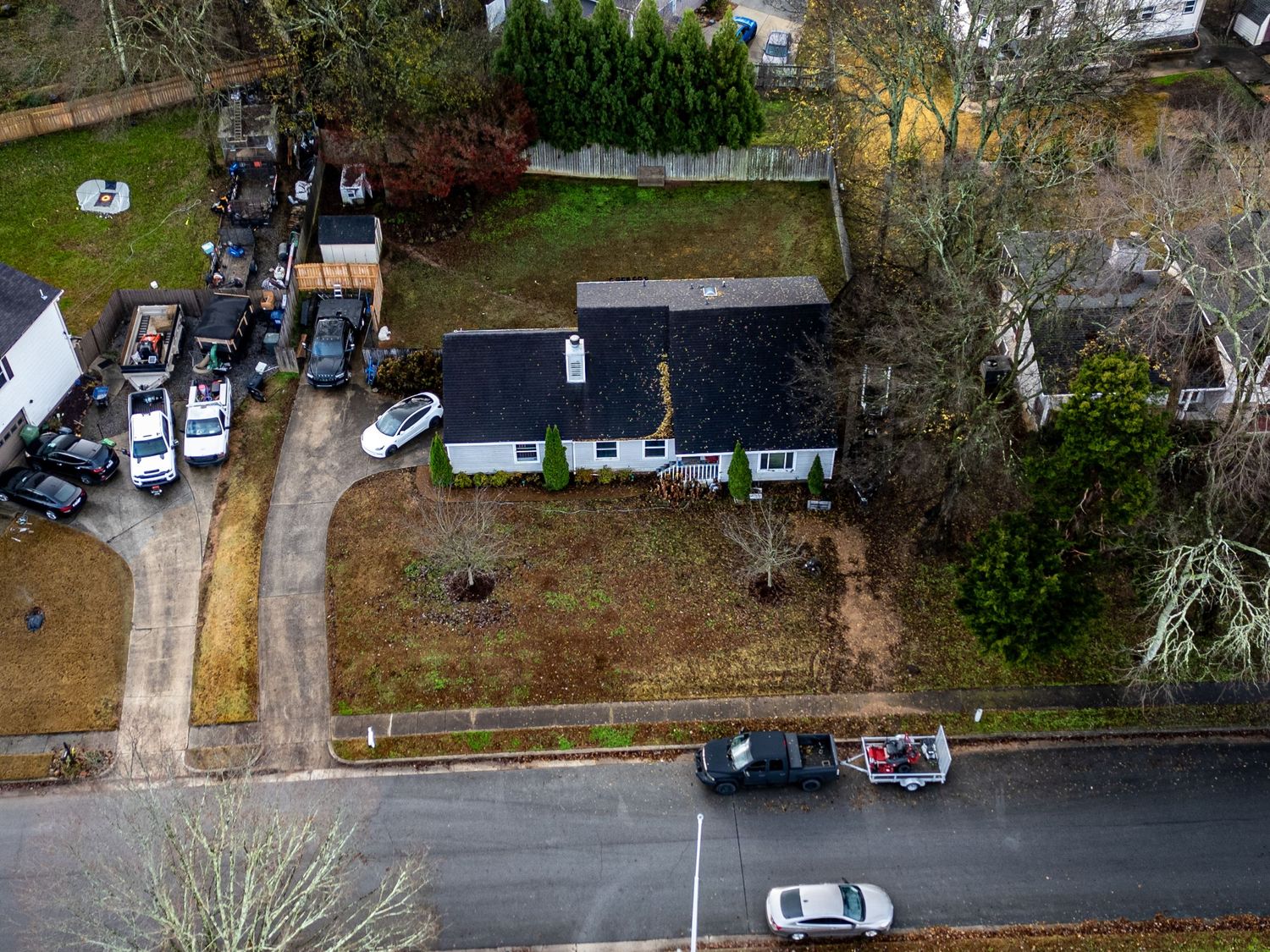 Bird's eye view of suburban streets and houses with parked cars and fall foliage.