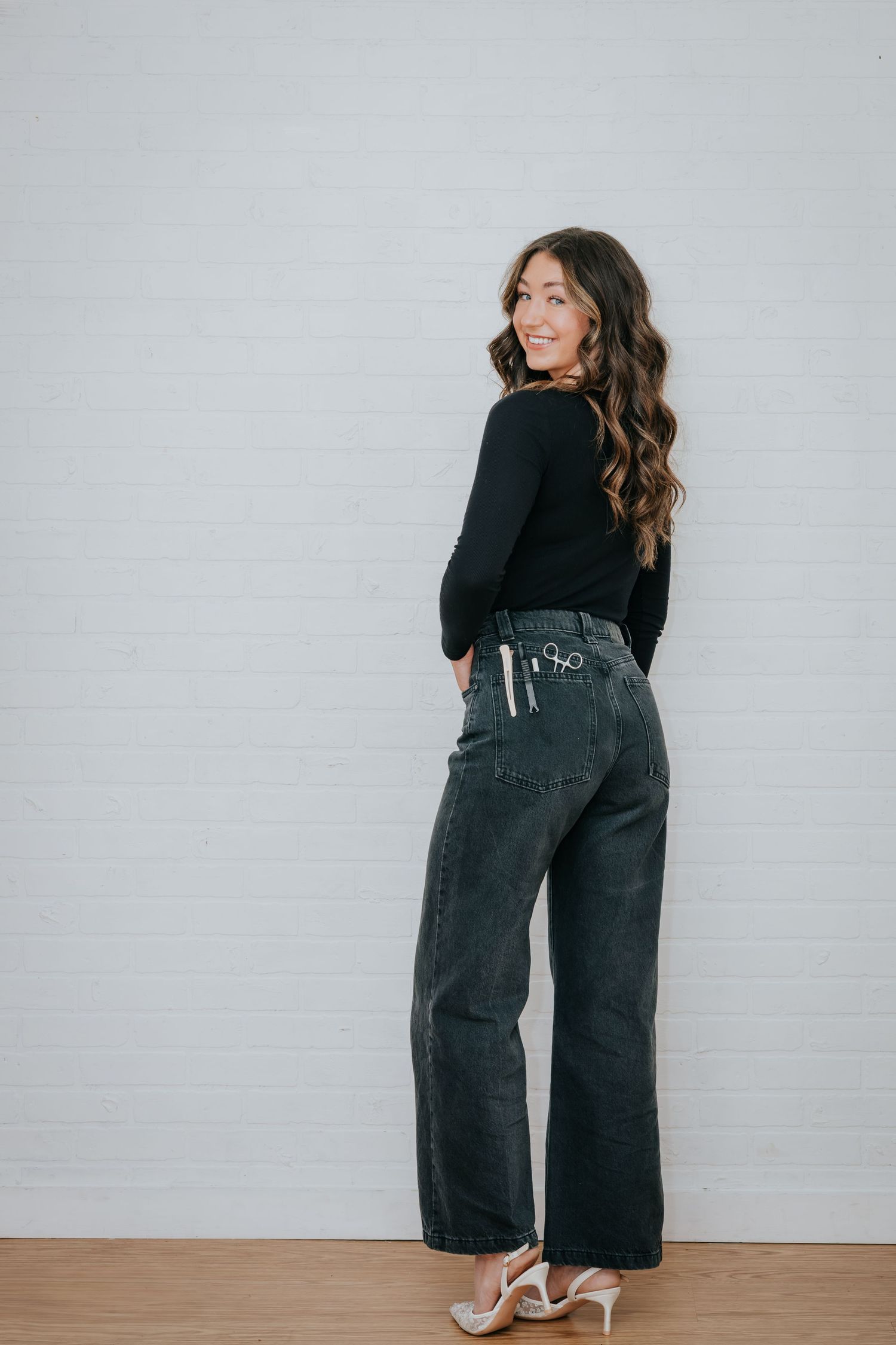 Multiple shots of someone wearing black jeans and a top posing against a white wall.