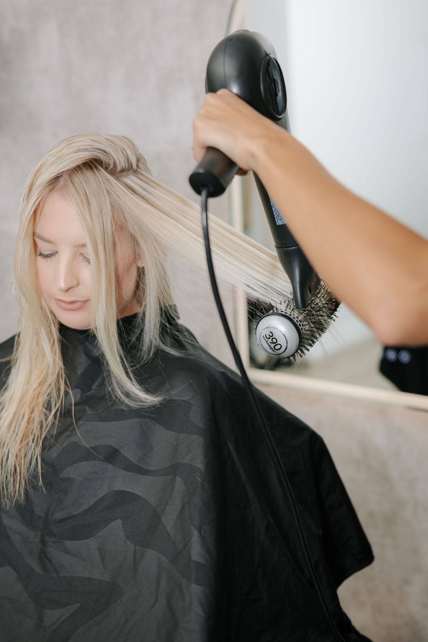 Hair styling session showing wet blonde hair being blow dried in a salon.