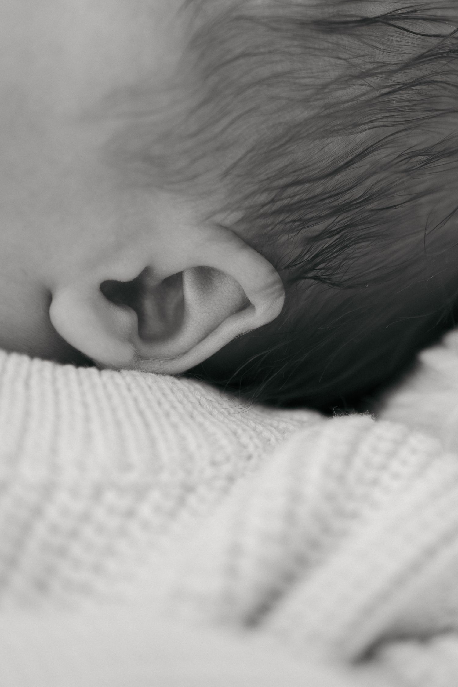 Abstract black and white close-up shots of a baby's ear and hair details.