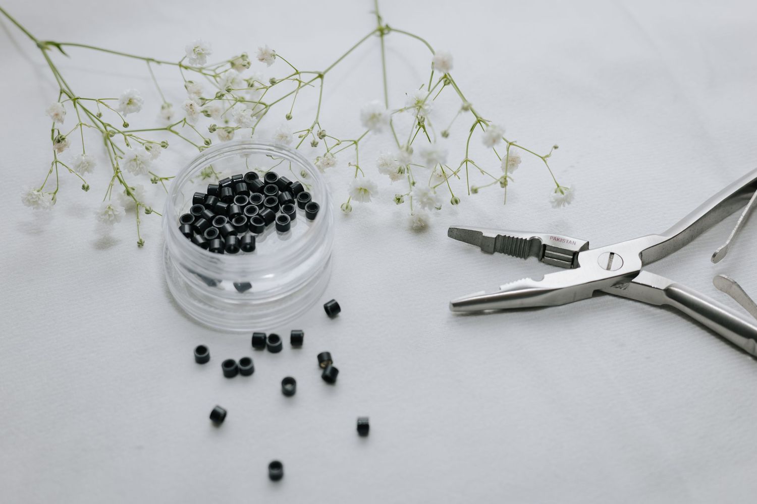 Minimalist arrangement of beauty tools and flowers on white surface.