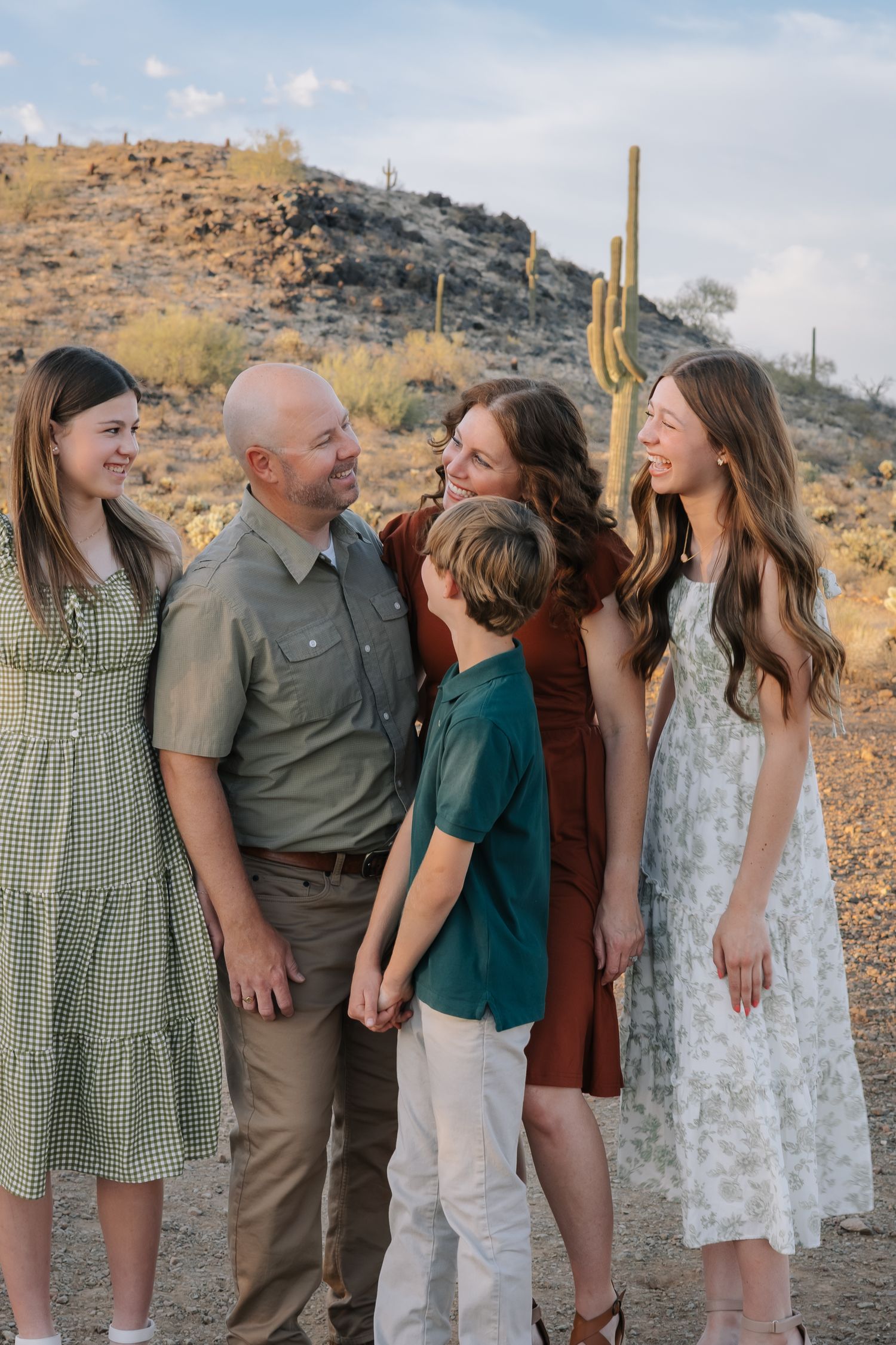 Family sharing a laugh together on desert trail with saguaro cactus and hills in background.