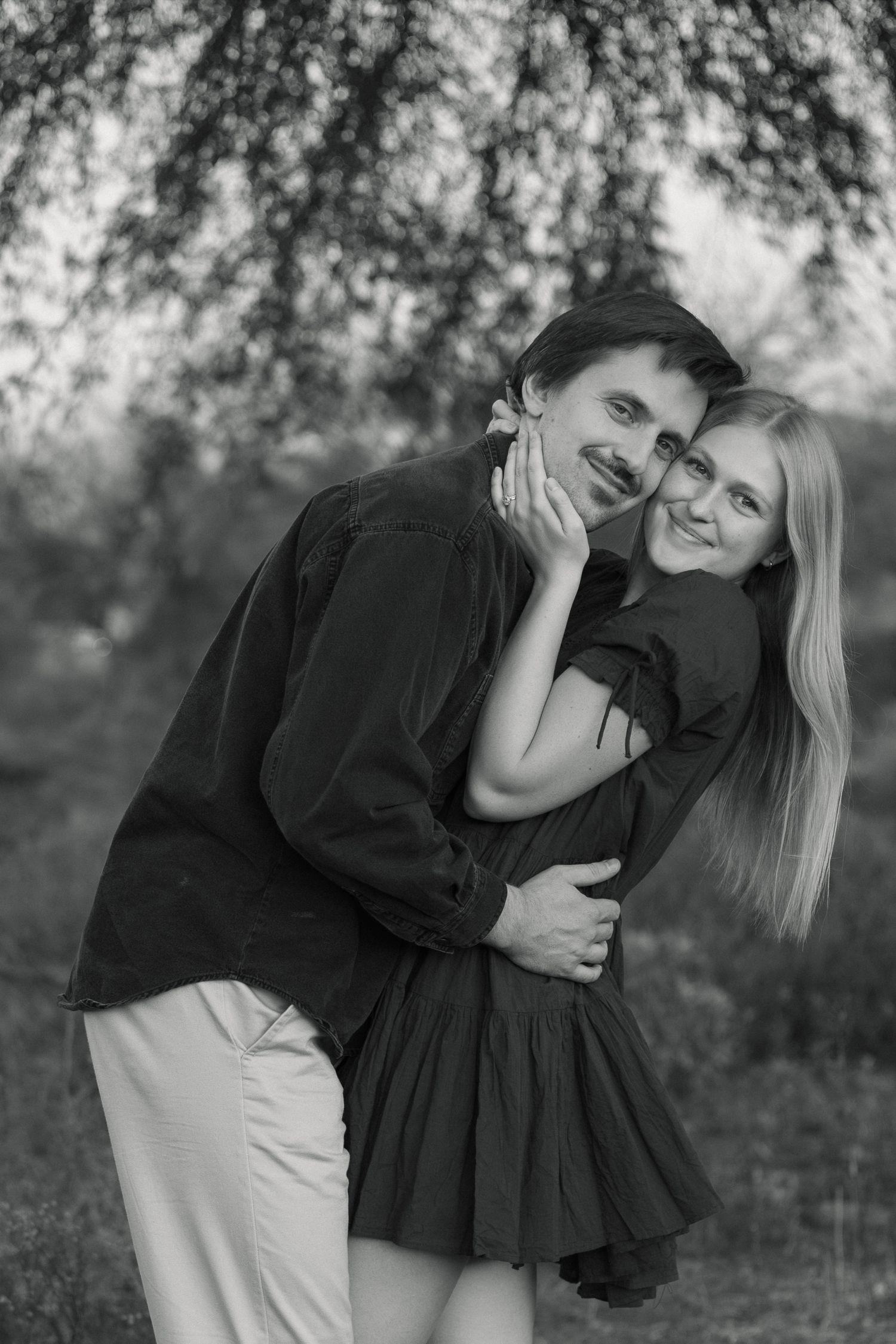 Two people sharing joyful moment together in black and white outdoor portrait.