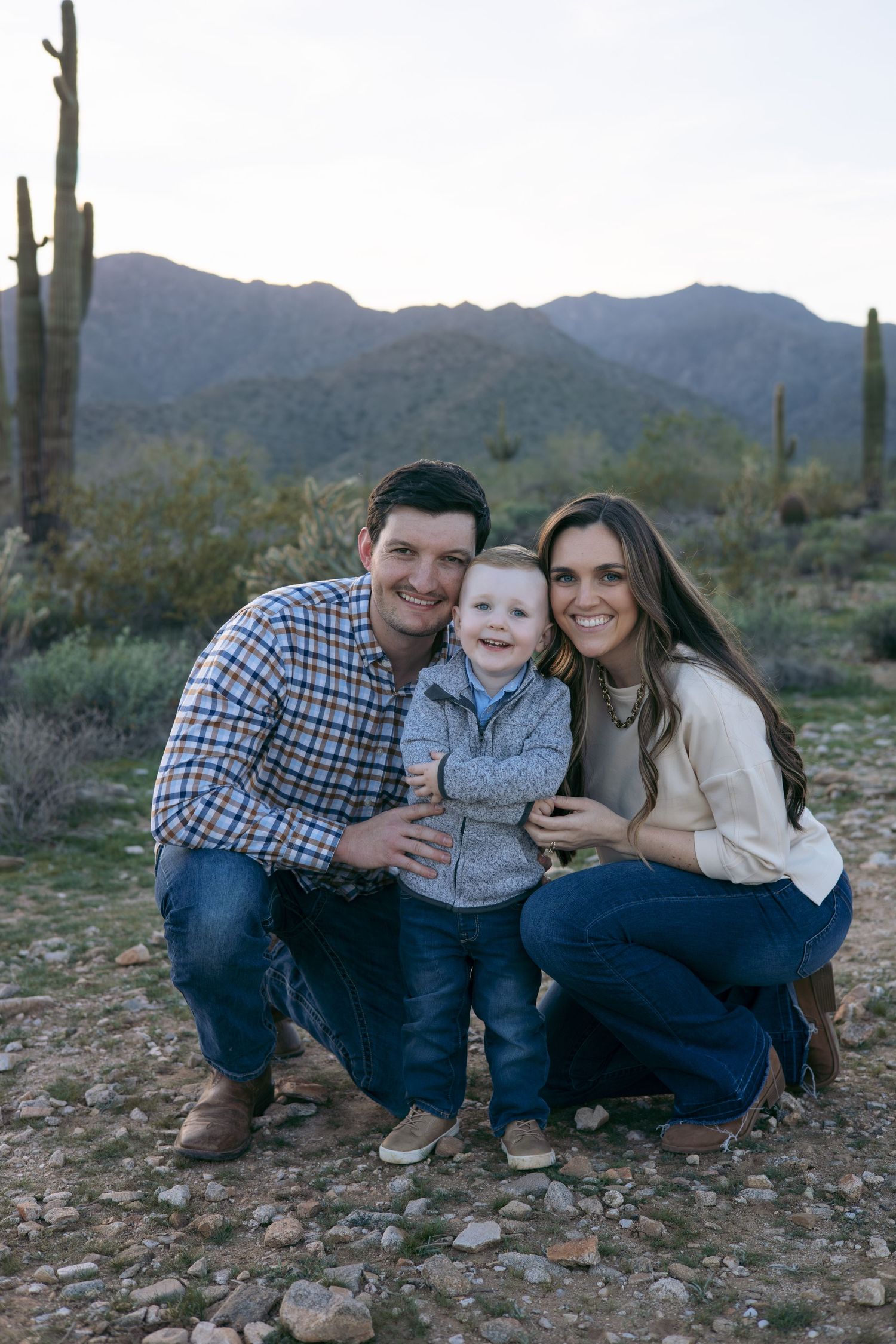 Desert family photoshoot with saguaro cactus and mountains in background.